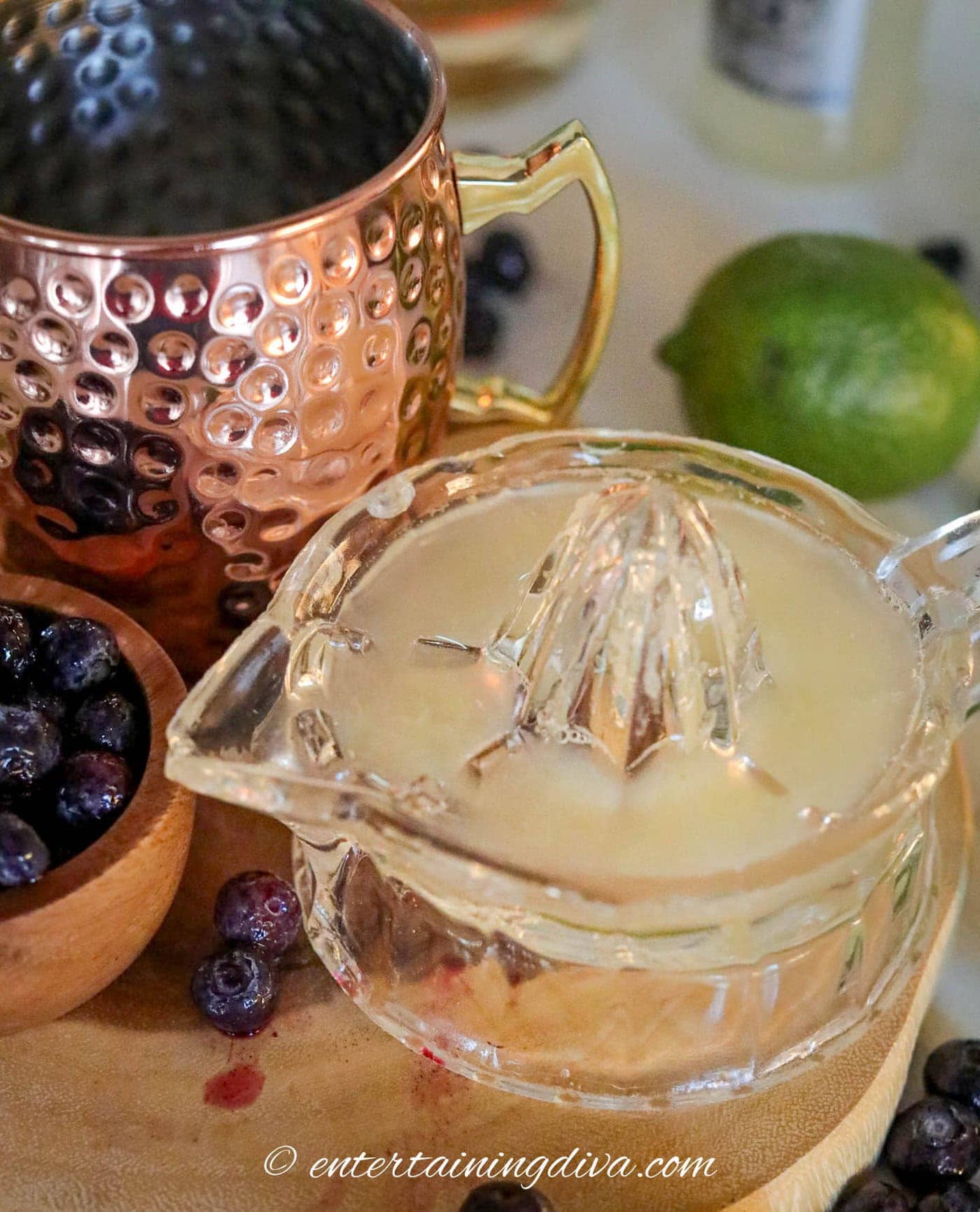 freshly squeezed lime juice in a juicer beside a copper mug