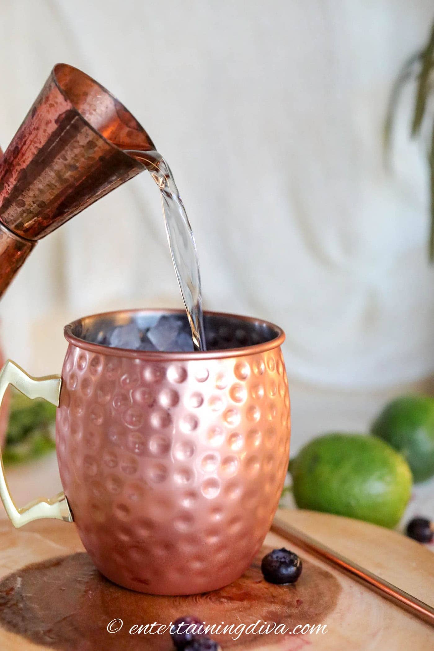 vodka being poured into a copper mug