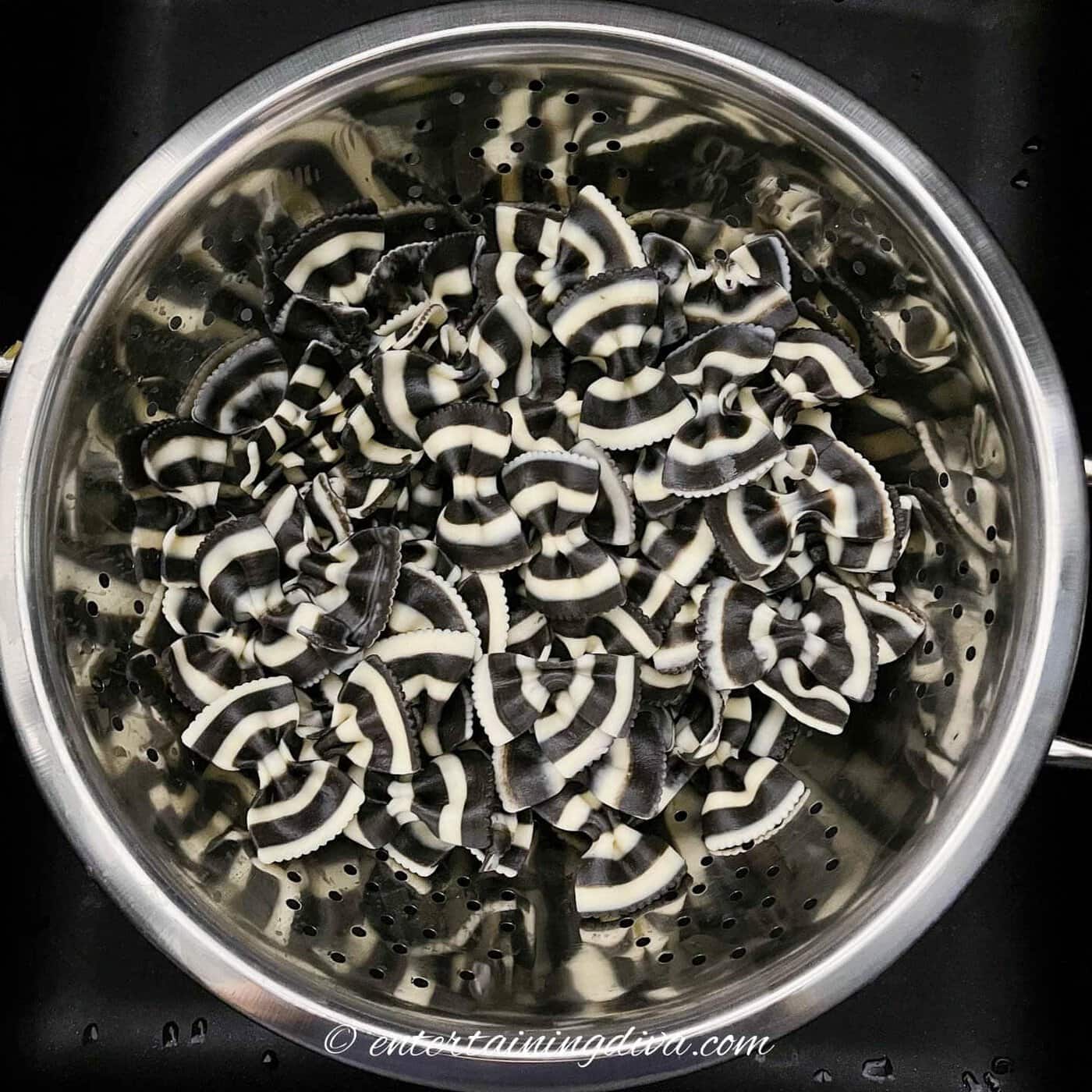 Cooked black and white bow tie pasta in a colander
