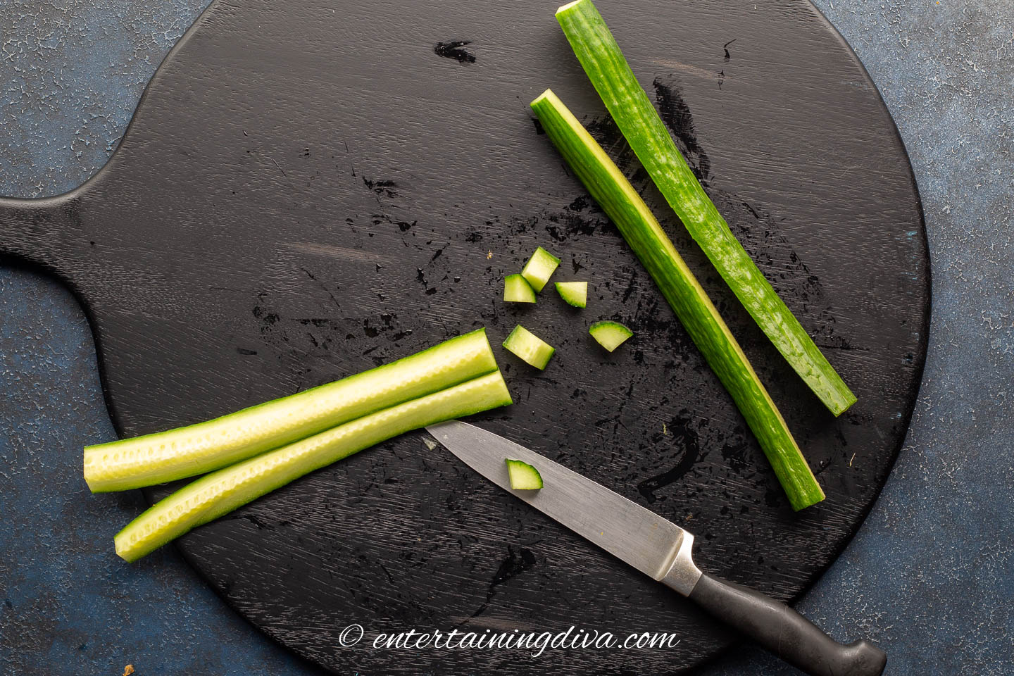 sliced and chopped English cucumbers on a cutting board with a knife
