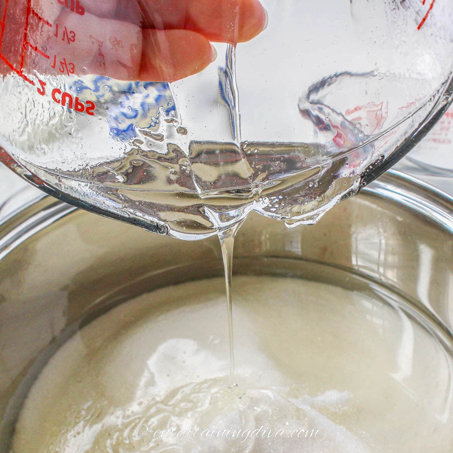 Corn syrup being poured into a sauce pan with sugar