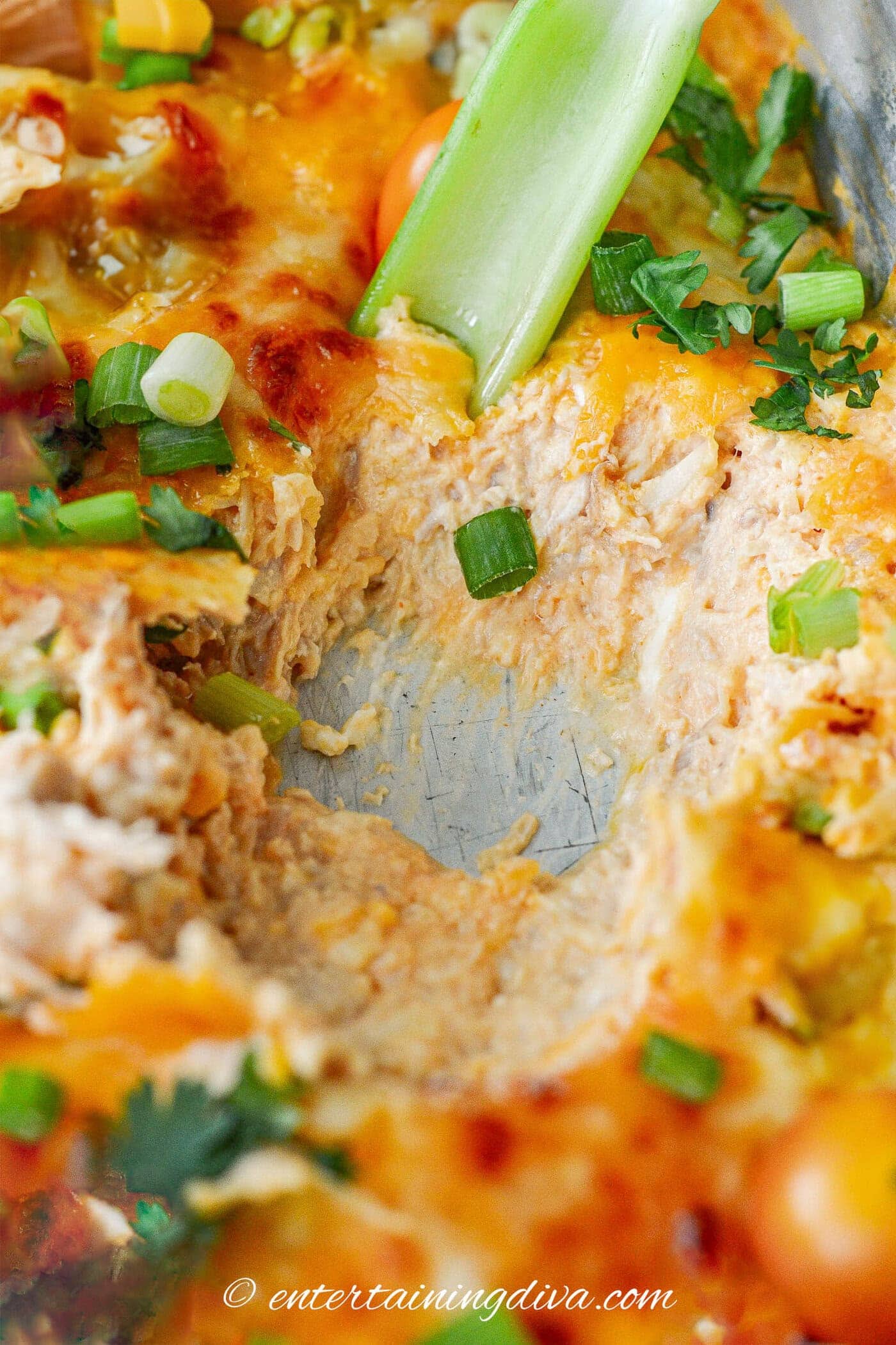 Buffalo chicken dip in a pan with a celery stick scooping it