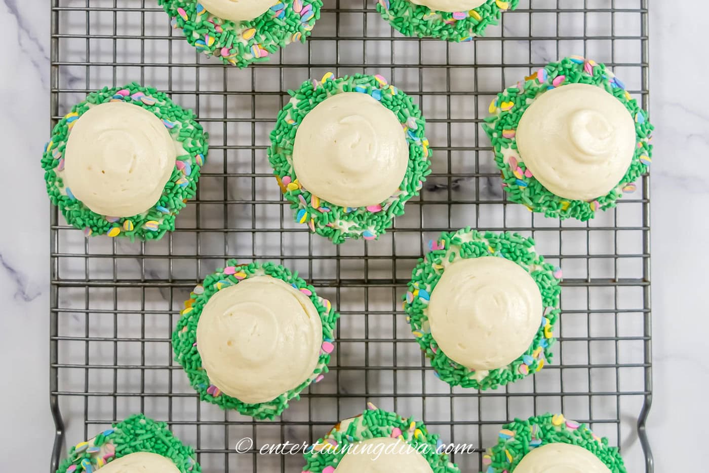cupcakes with green sprinkles and a dollop of white frosting