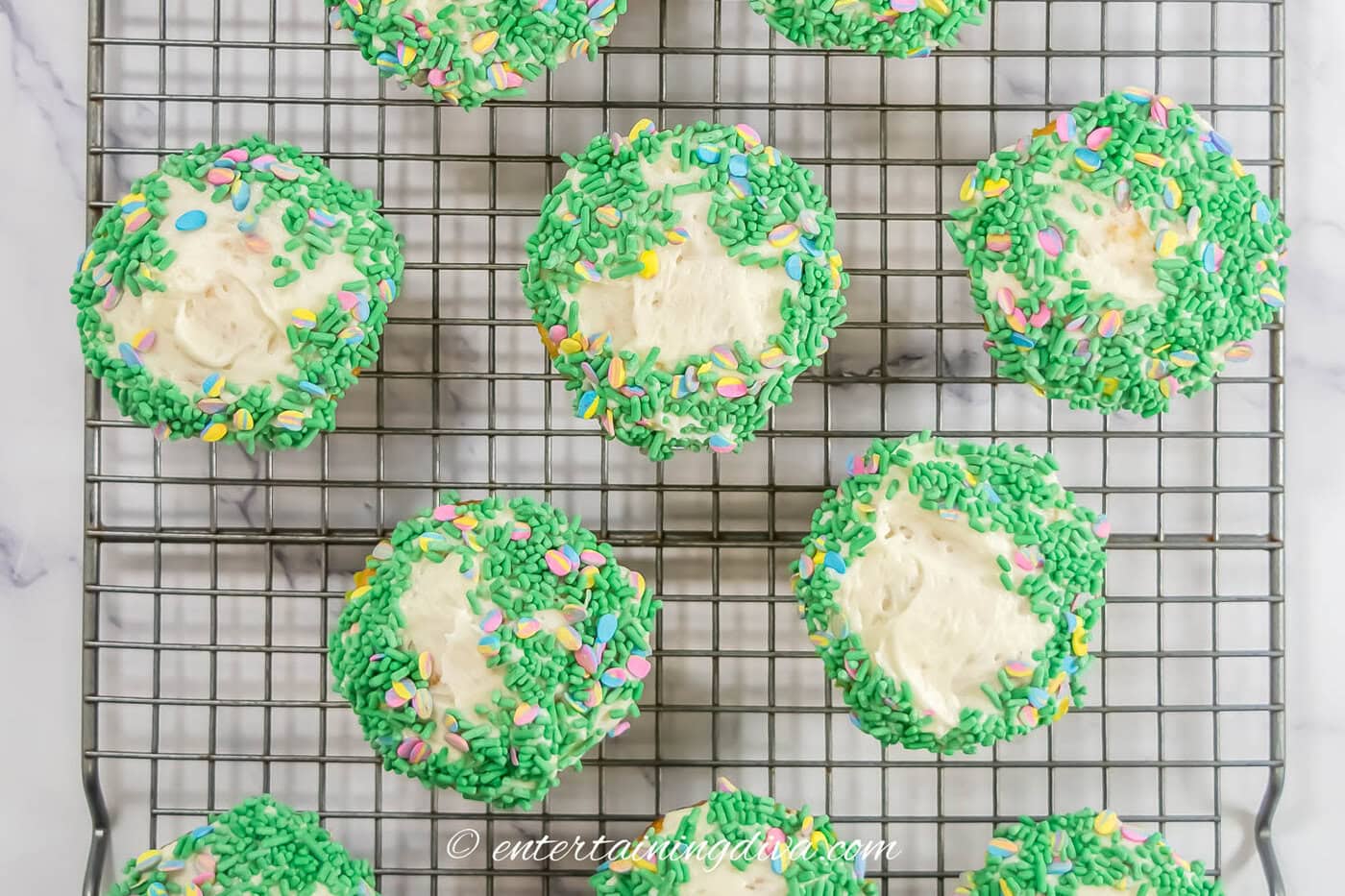 cupcakes with white frosting and green sprinkles on top