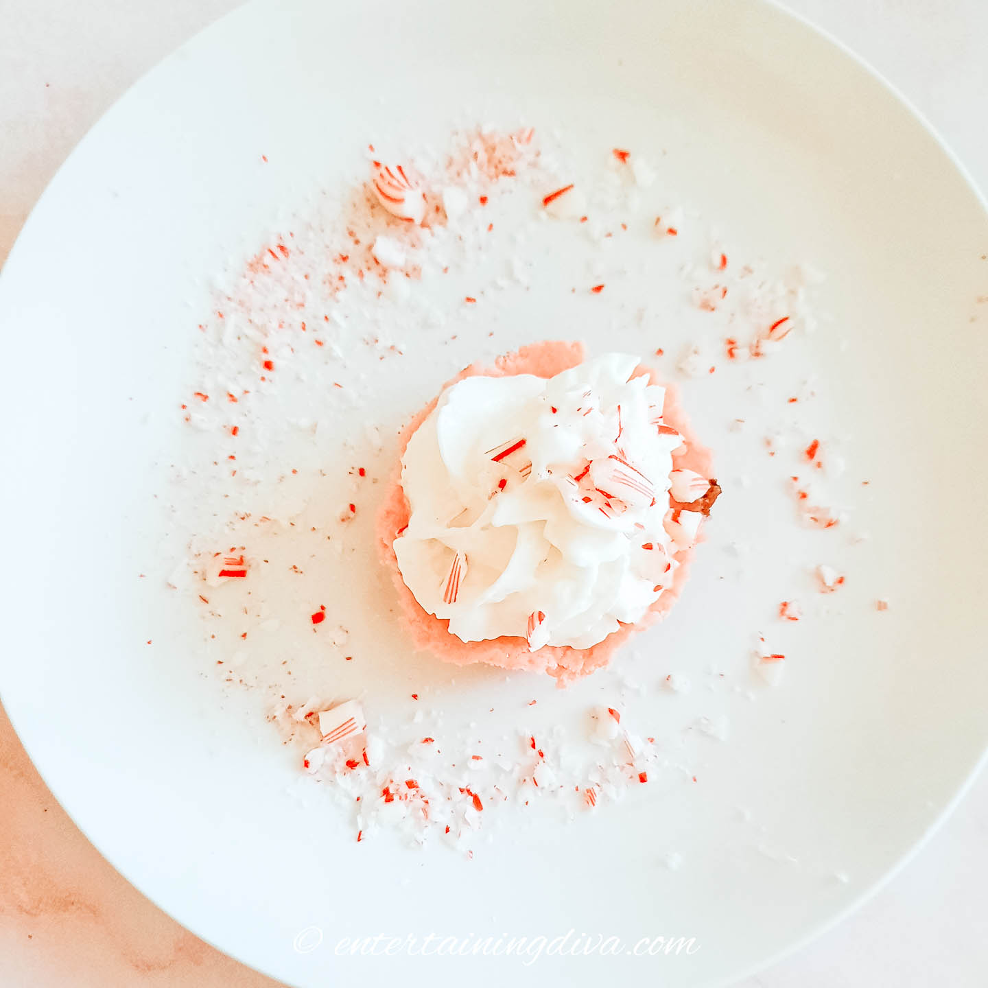 Top view of a candy cane peppermint cheesecake cupcake on a plate