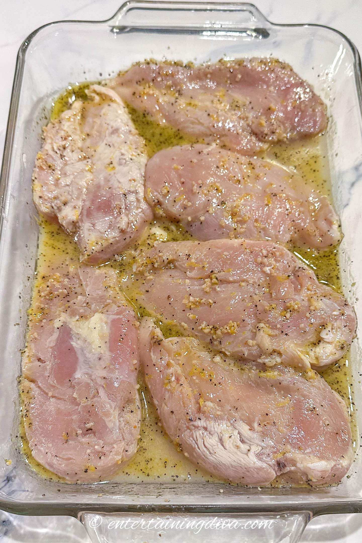 chicken breasts marinading in a glass dish