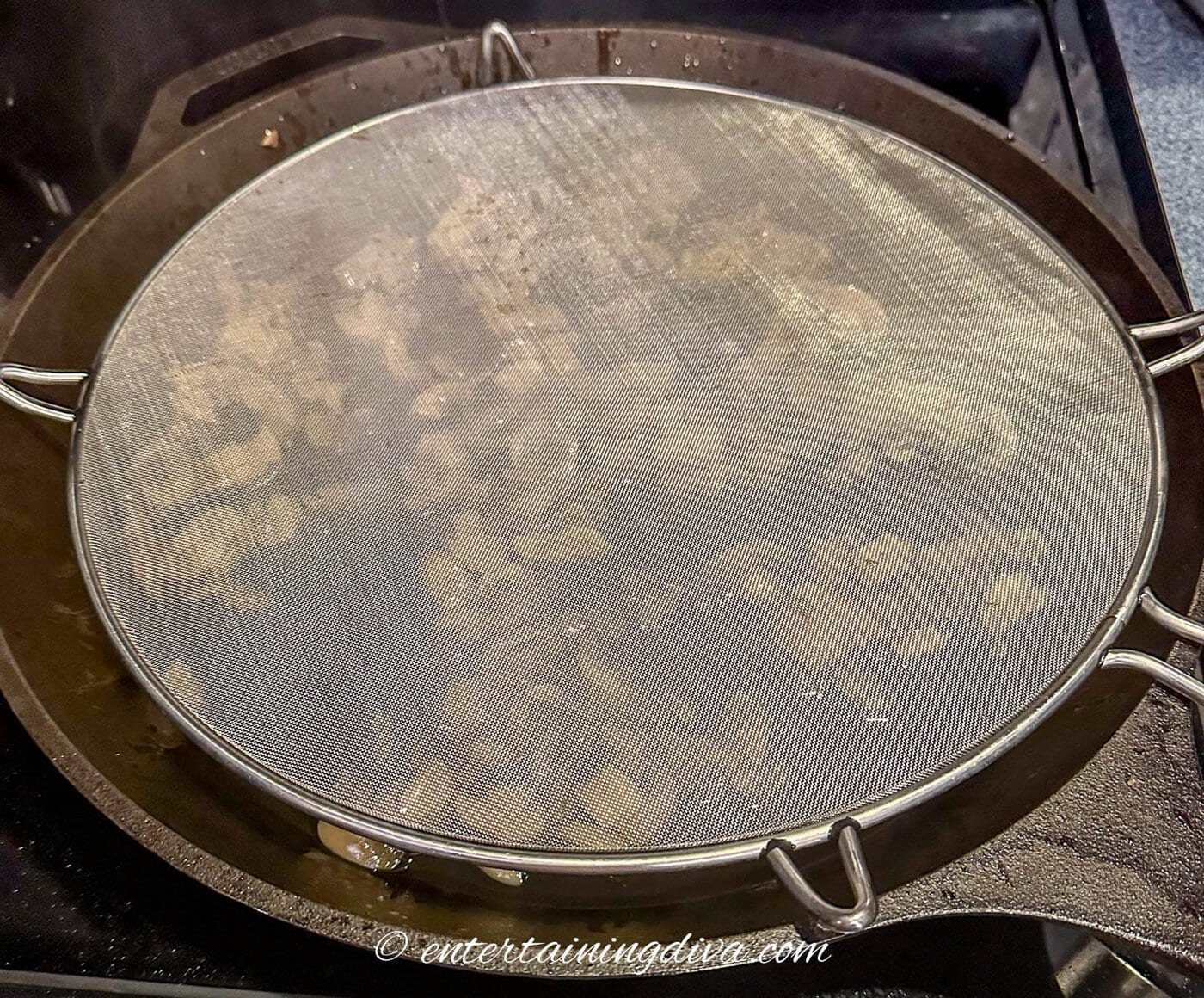 cast iron pan covered with a splatter screen