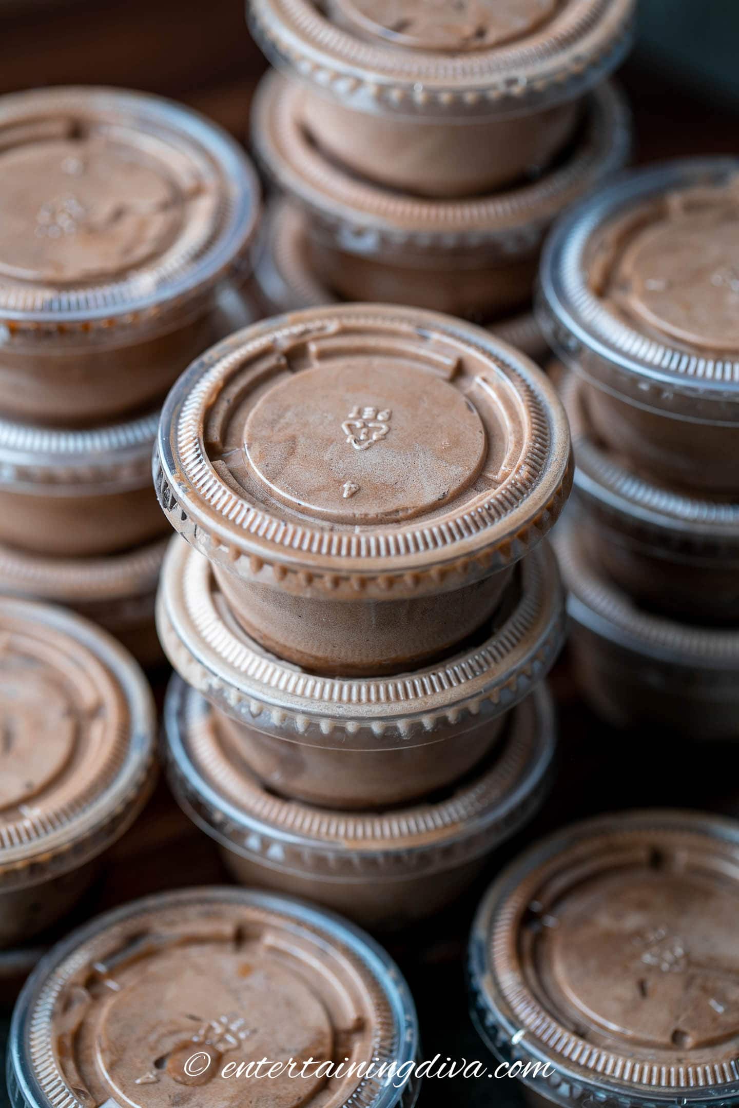 Stacks of peanut butter chocolate pudding shots in plastic shot cups with lids