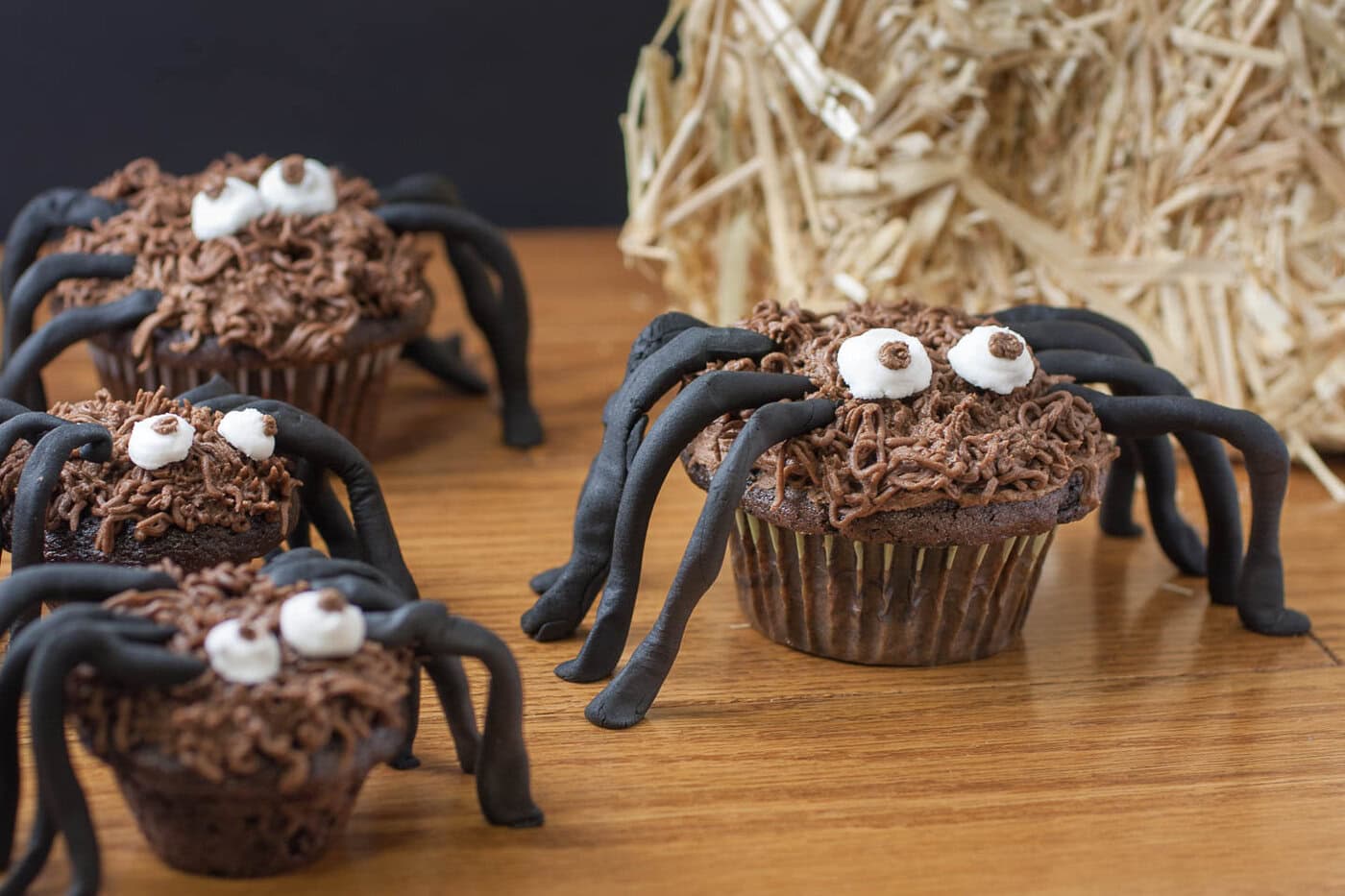Chocolate spider cupcakes with black fondant legs and chocolate frosting