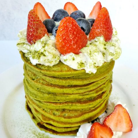 stacked matcha pancakes with whipped cream and fresh fruits