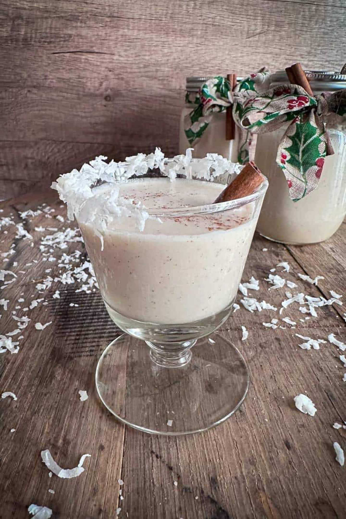 A glass with whipped cream and cinnamon sitting on top of a wooden table.