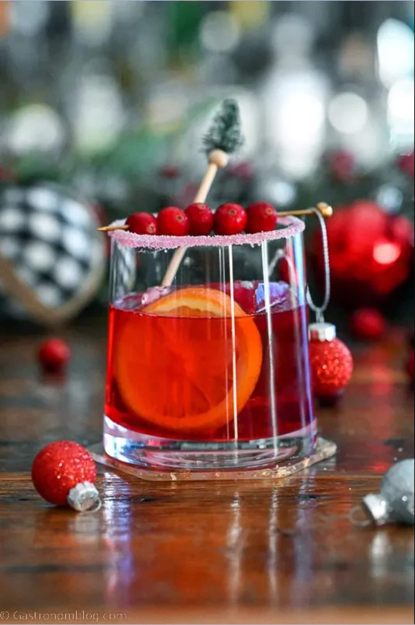 A red drink with cranberries and ornaments on a table.