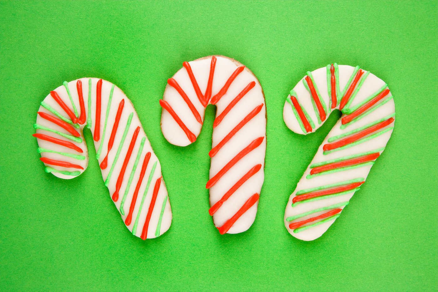 Three candy canes sugar cookies on a green background
