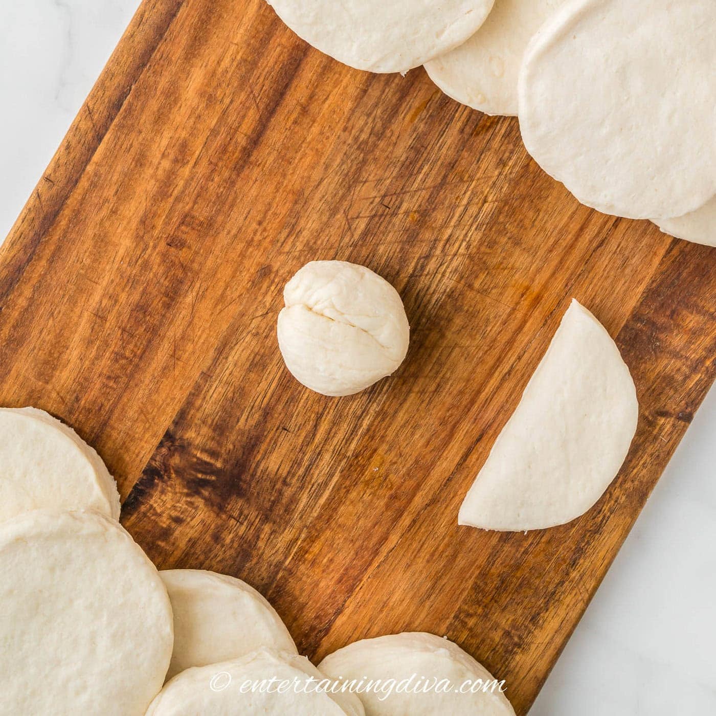 half a biscuit rolled into a ball on a cutting board with other biscuits