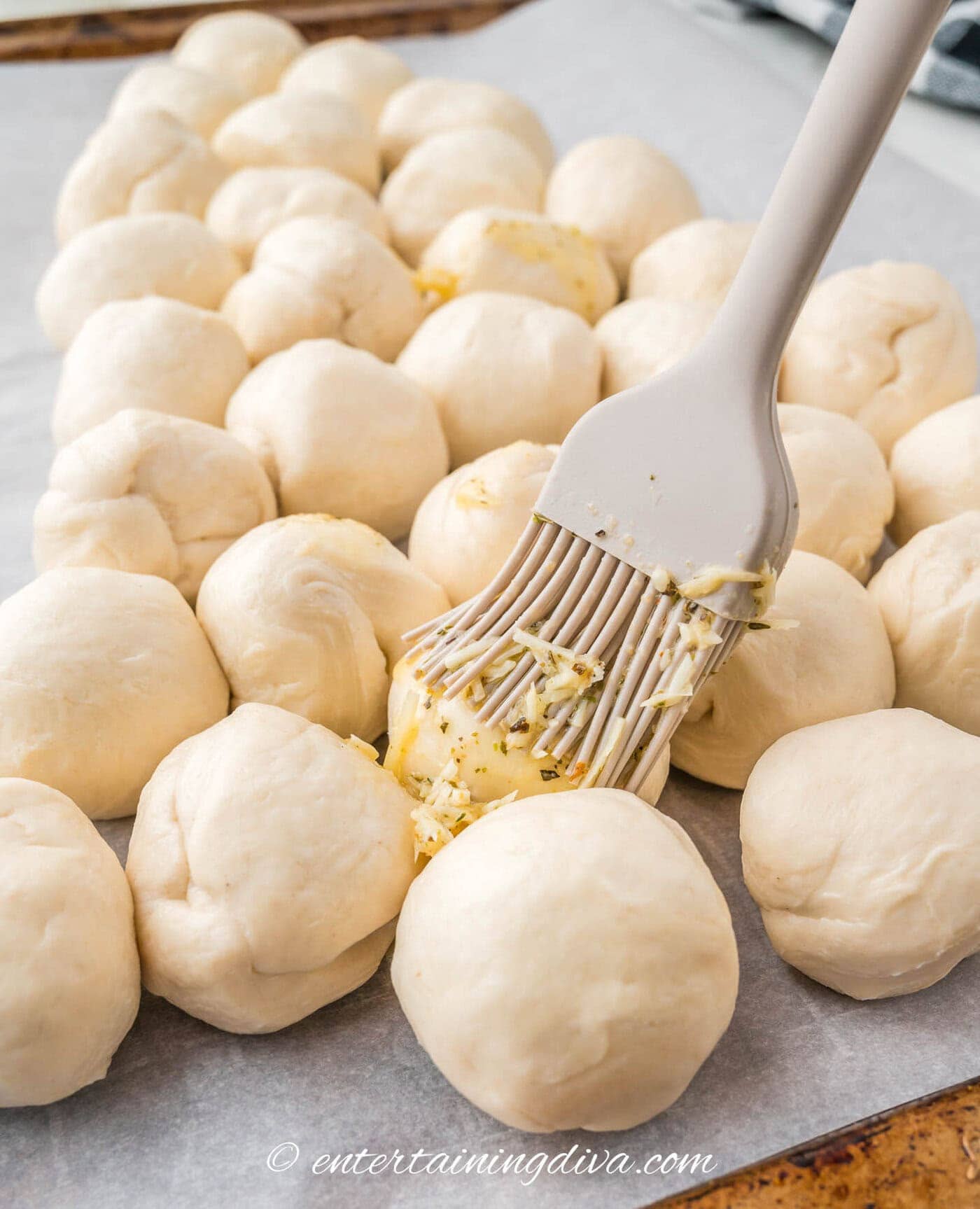 garlic butter being brushed onto cheesy pull apart bread with a pastry brush