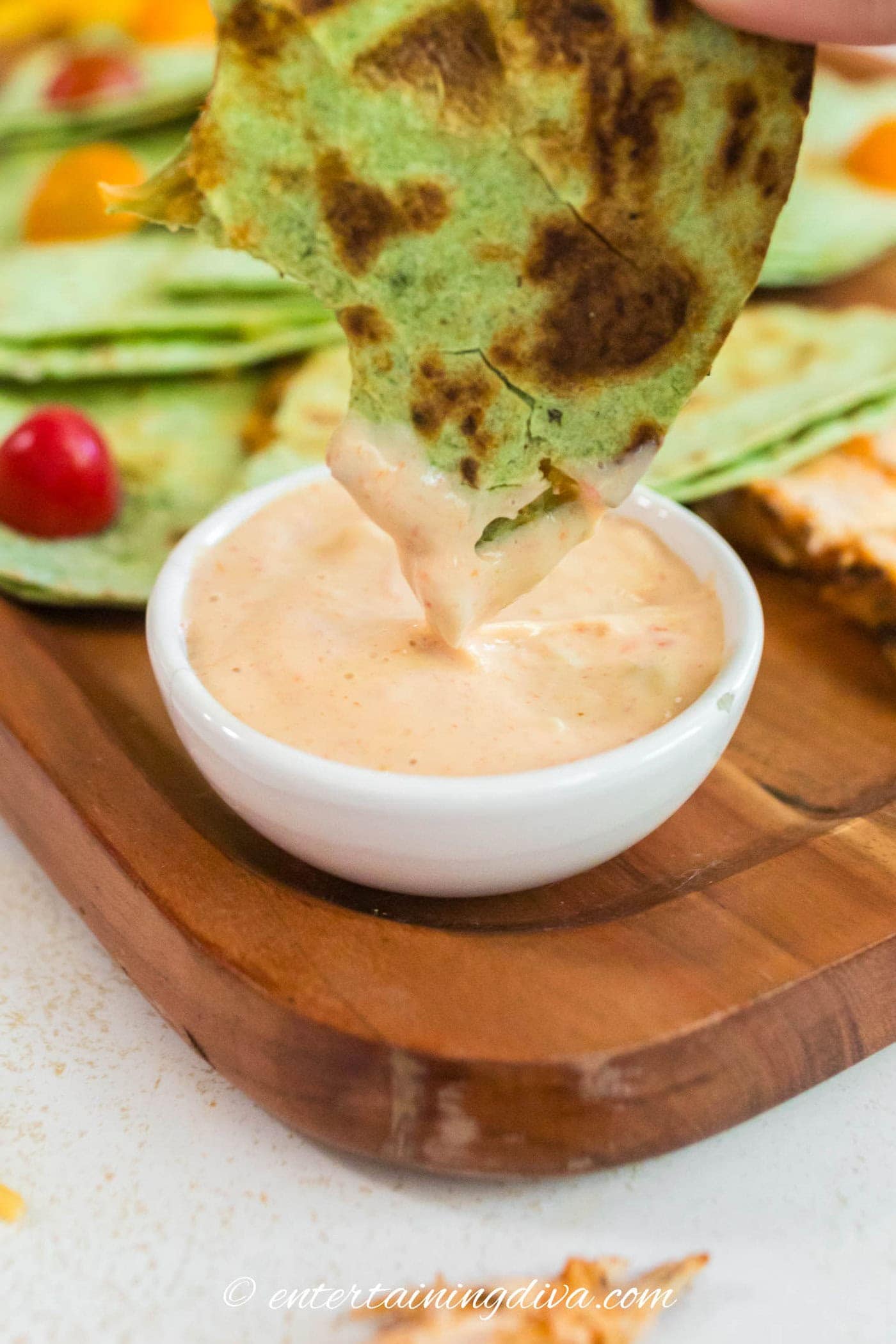 A quesadilla being dipped in queso