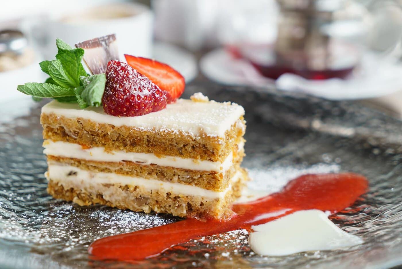 carrot cake with cream cheese frosting, and garnished with strawberries and mint