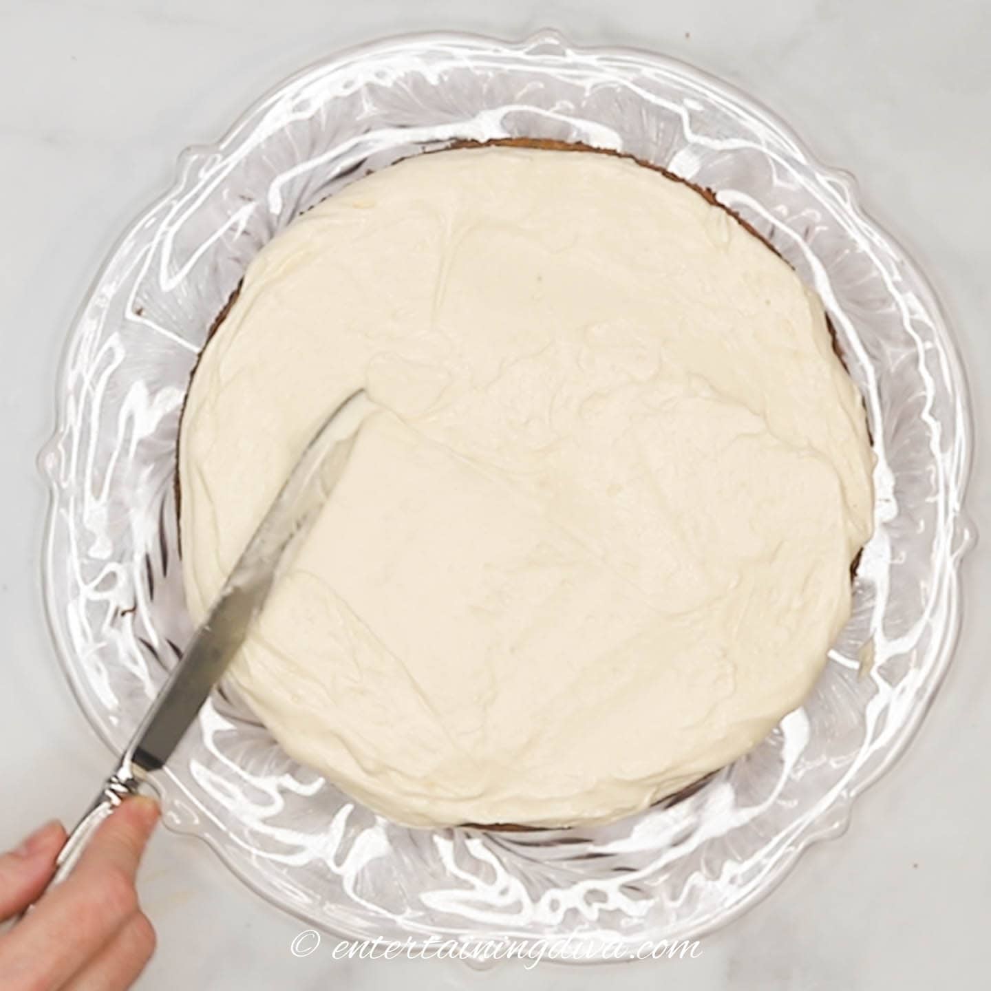 Cream cheese frosting being spread on a carrot cake