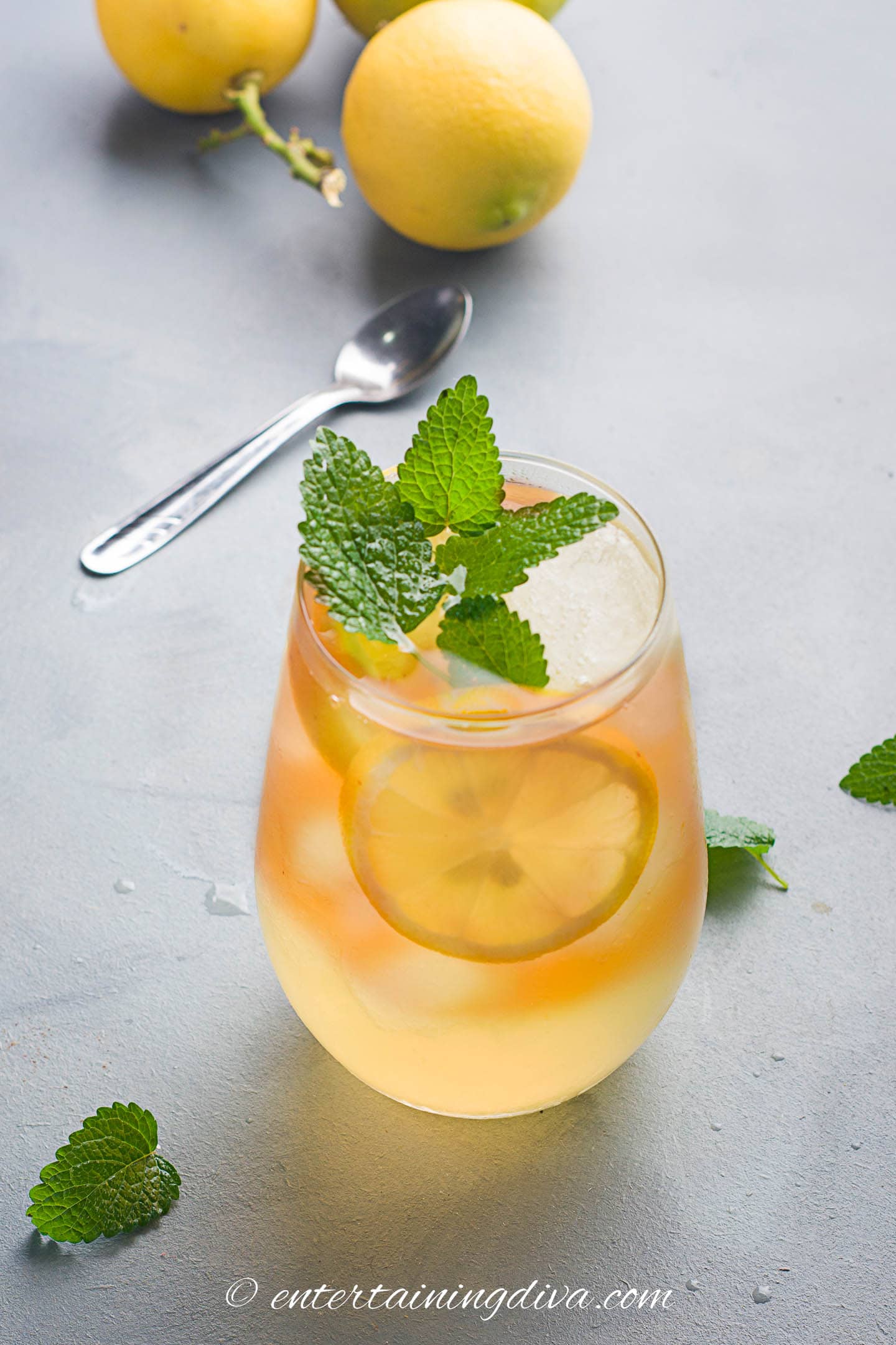 A glass of cold brew lemon iced tea garnished with a lemon slice and a sprig of fresh mint