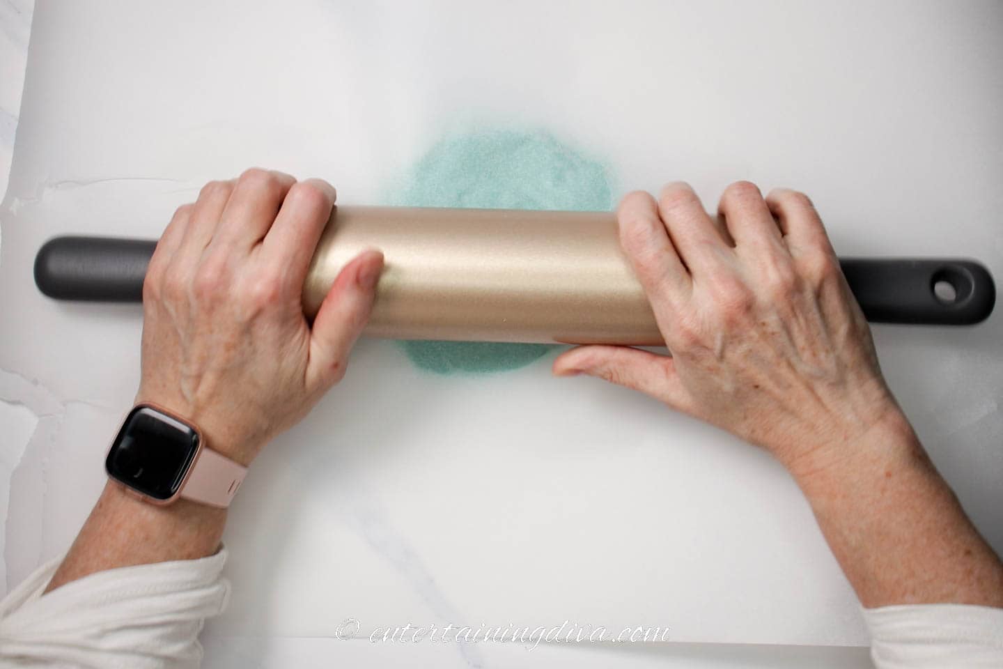 Blue cookie dough being rolled out by a rolling pin