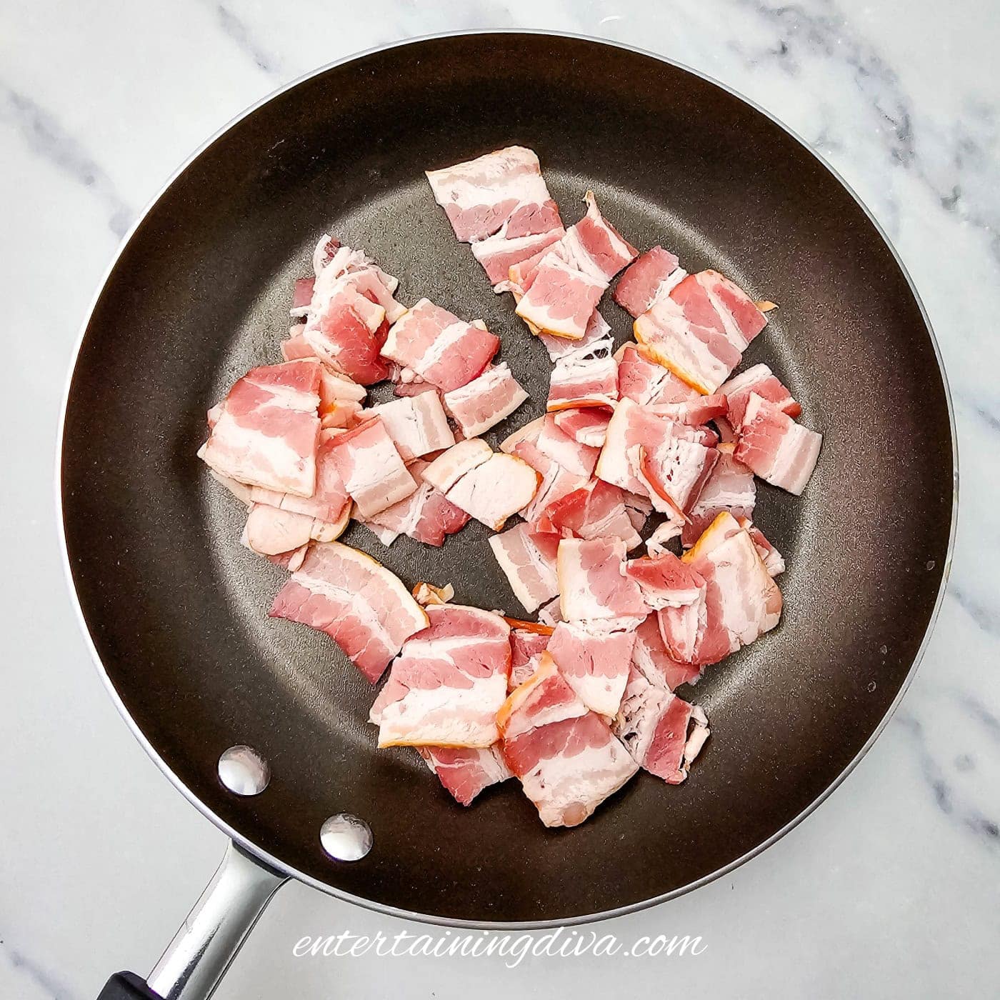 Uncooked chopped bacon pieces in a nonstick frying pan.