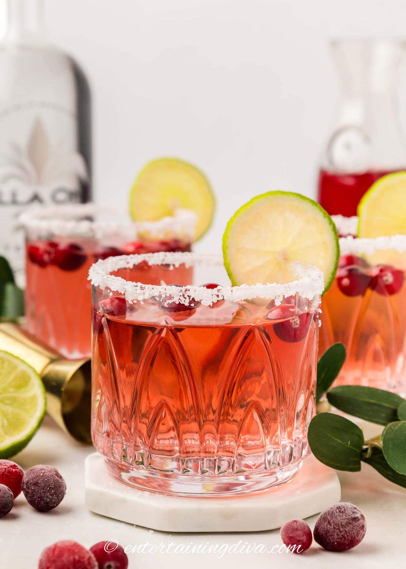 Three Christmas cranberry margaritas garnished with a salt rim, a lime wheel and fresh cranberries