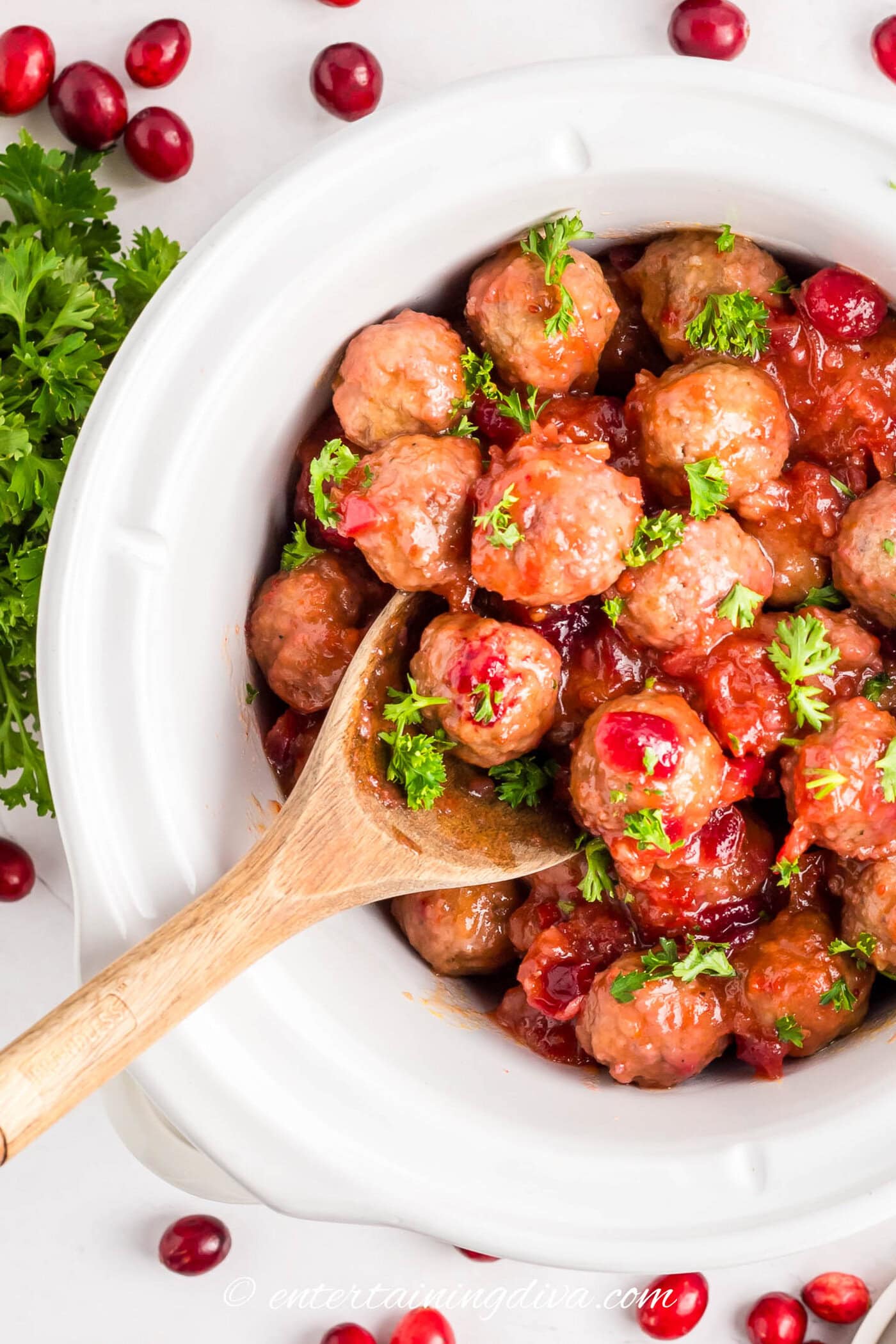 chili sauce cranberry meatballs garnished with parsley in a crockpot