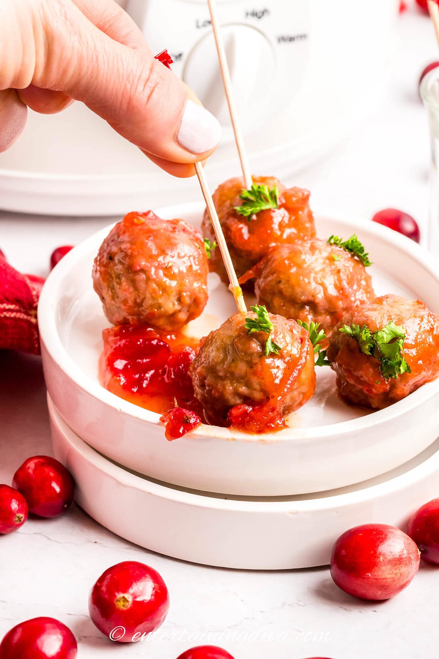 cranberry meatballs on a dish being picked up with a toothpick