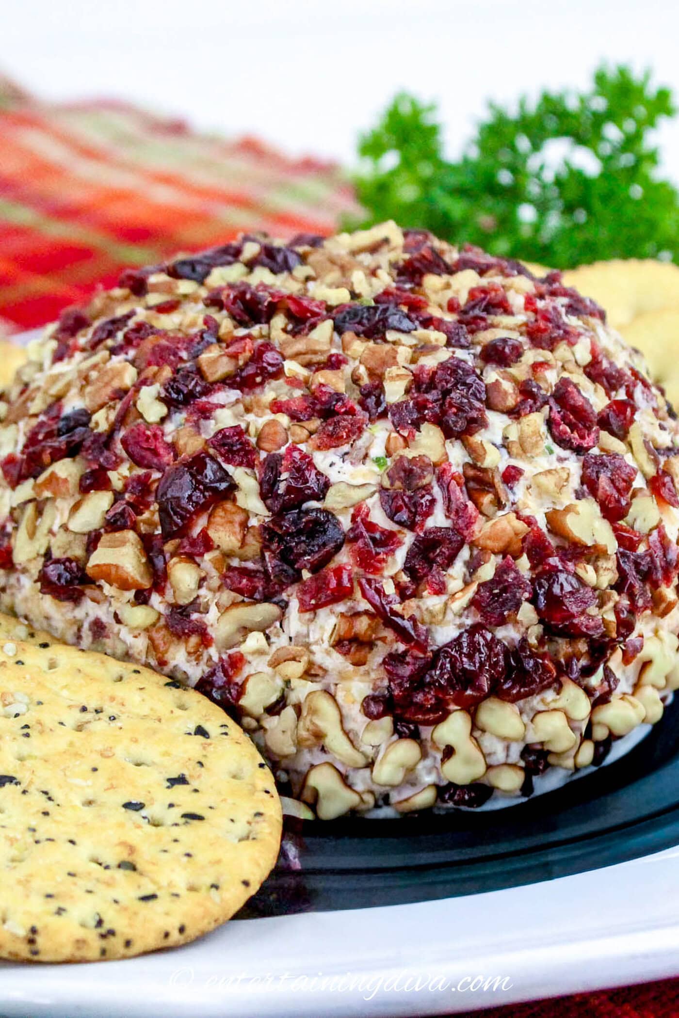 cranberry pecan cheese ball on a plate with crackers