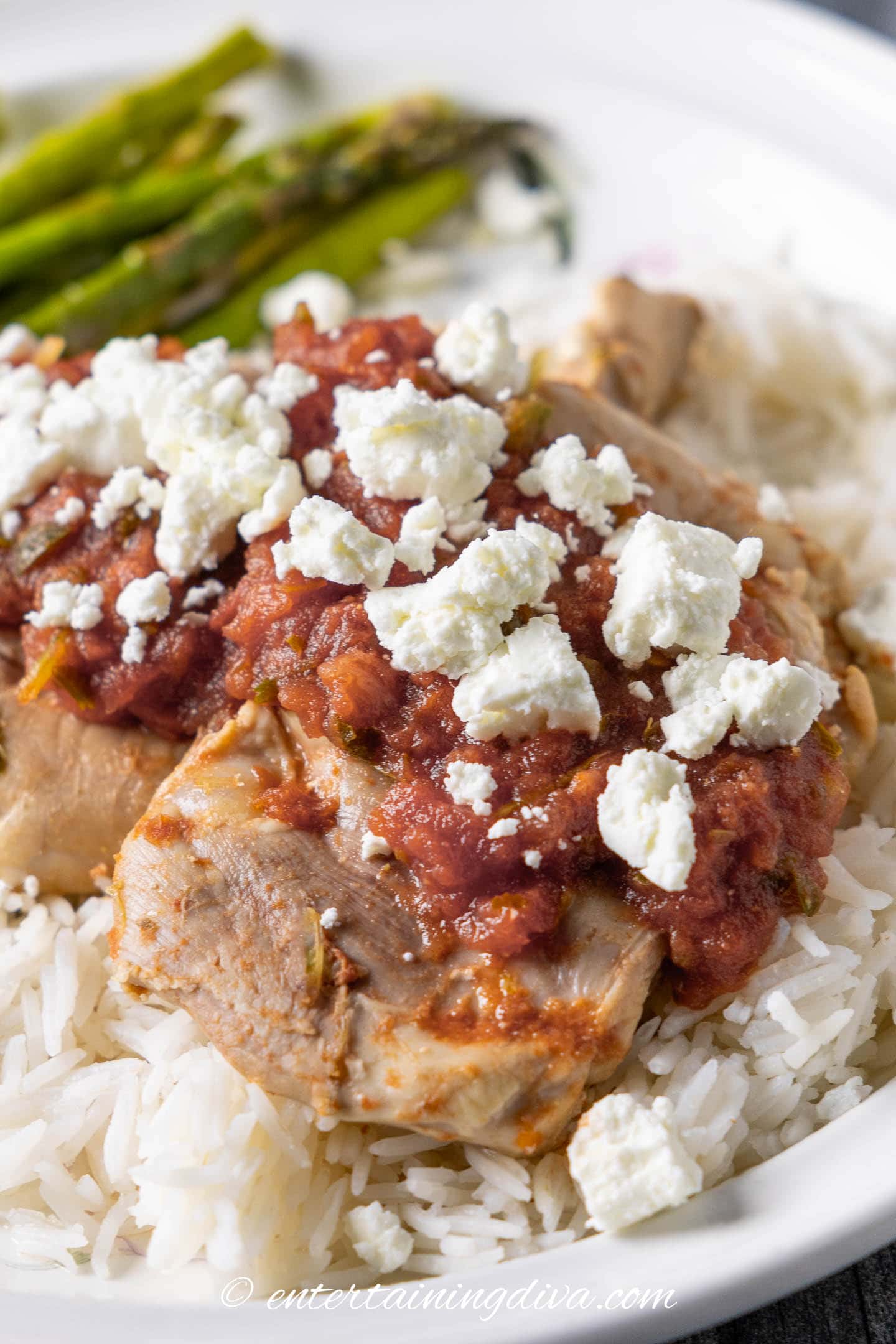 close up of crockpot salsa chicken topped with goat cheese on a plate