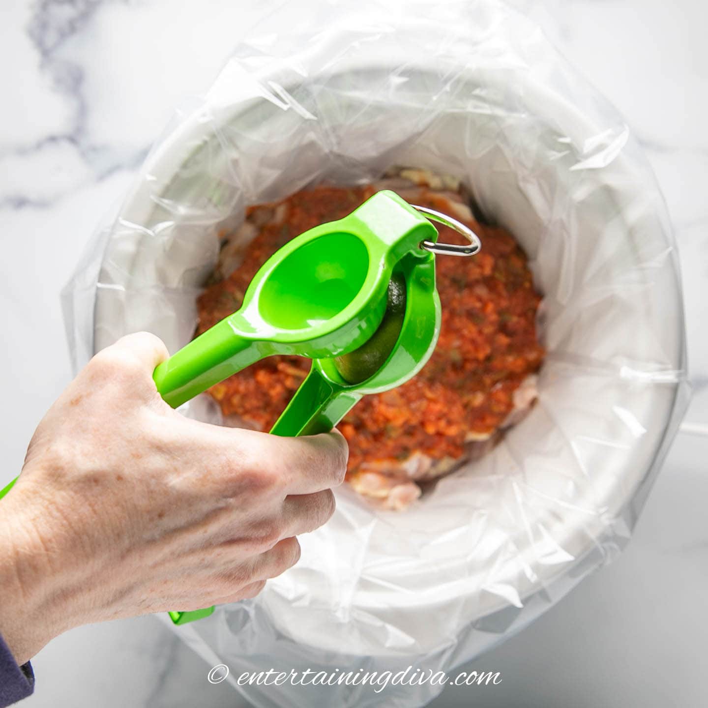 lime being squeezed into a crock pot with chicken and salsa