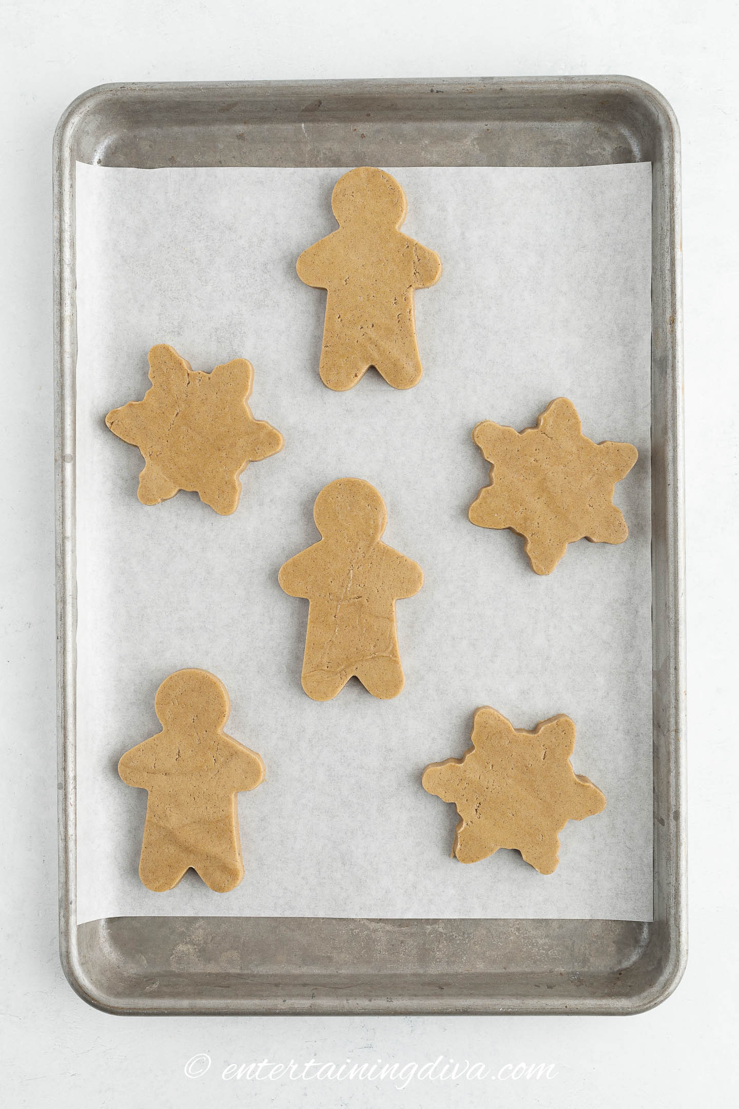 gingerbread men and snowflakes on a cookie sheet before baking