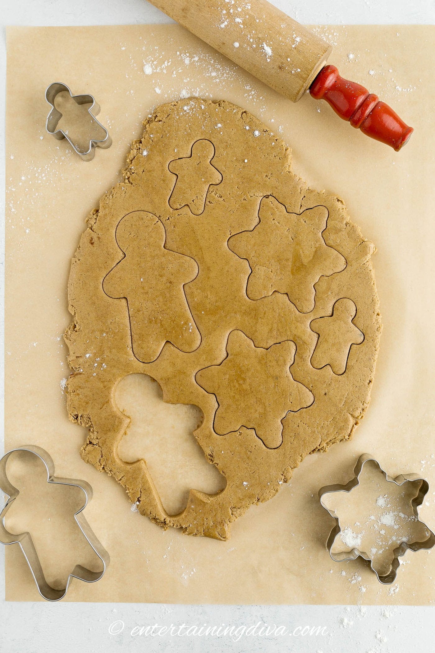 gingerbread men and stars being cut out of rolled gingerbread cookie dough