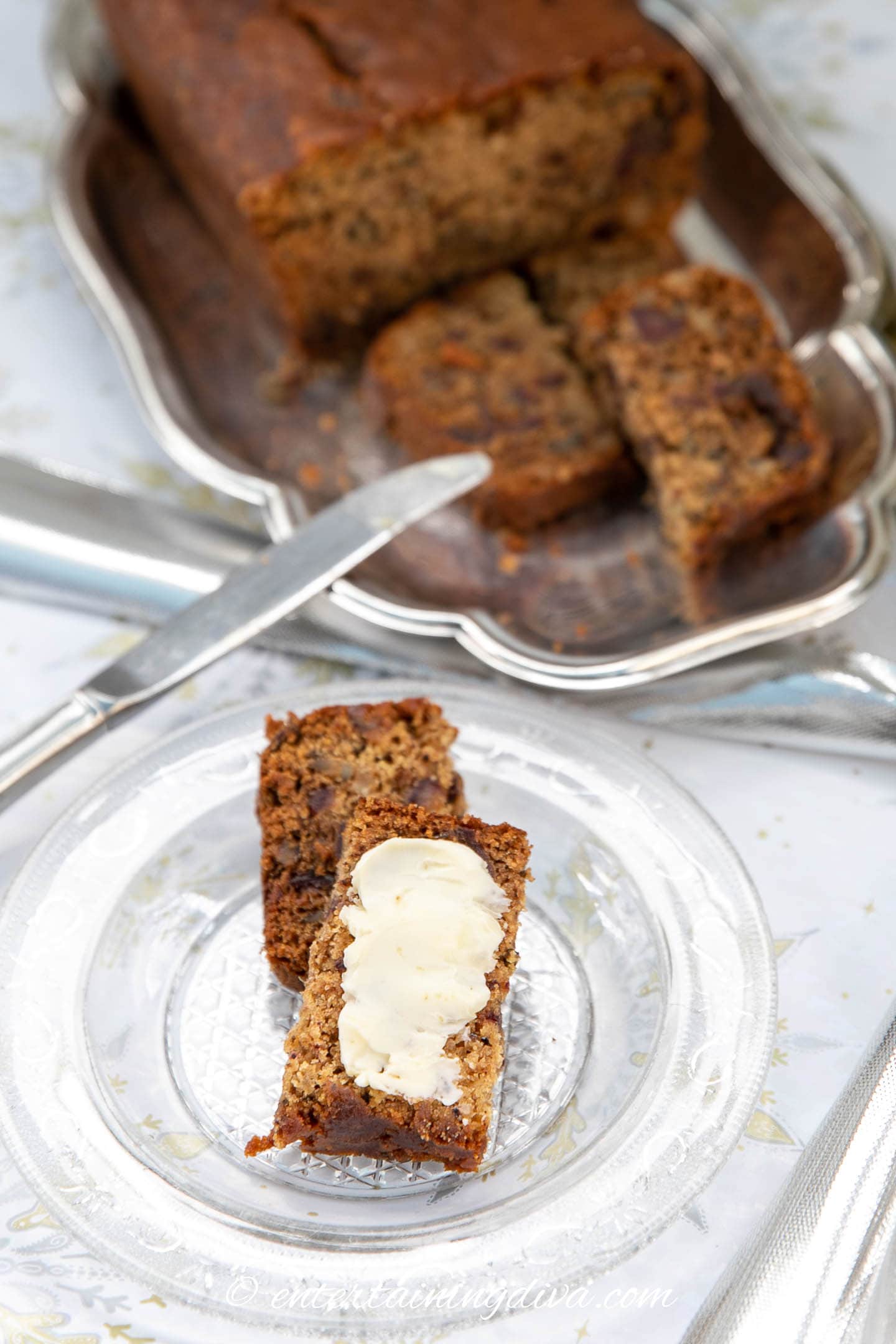 Slices of date walnut bread served with butter on a plate