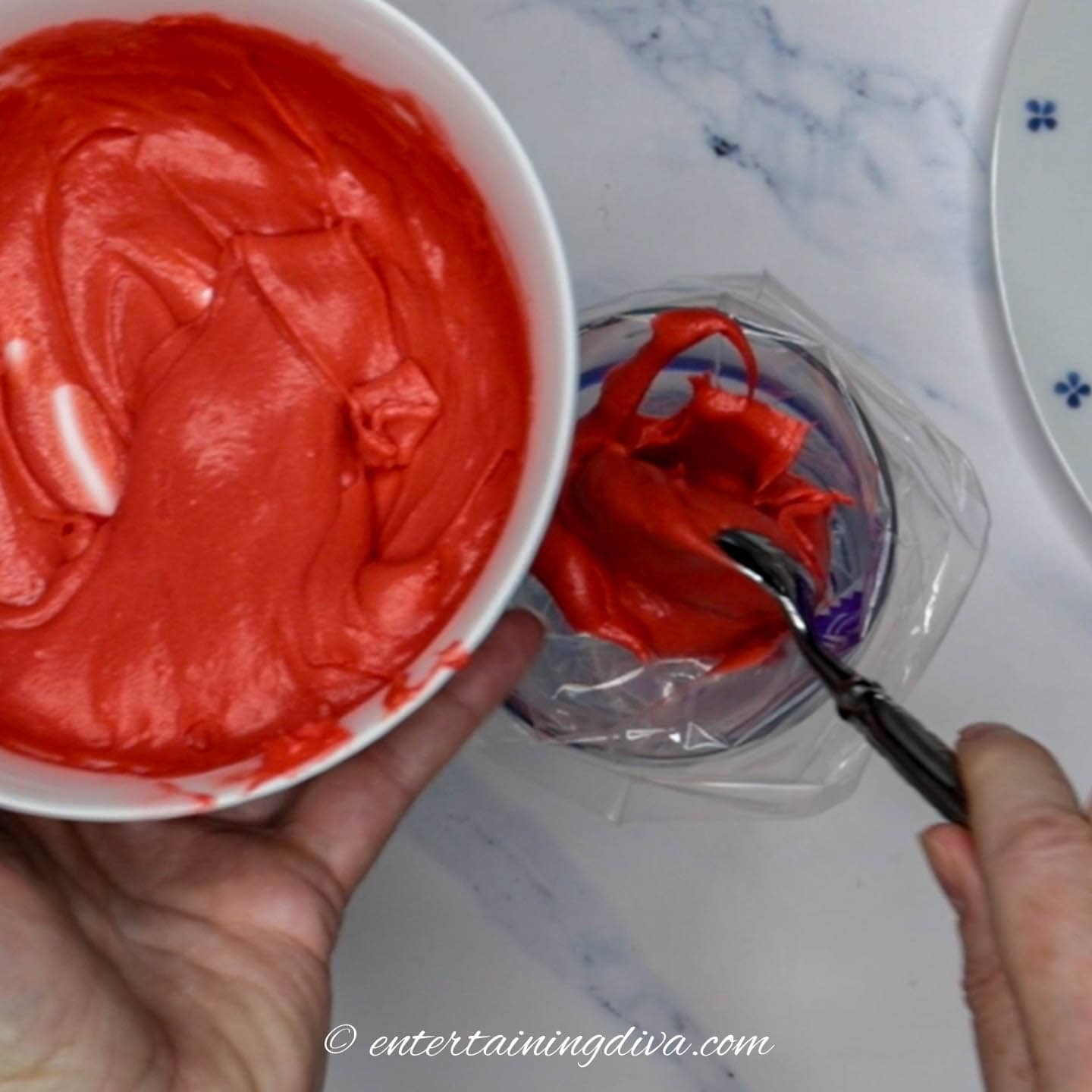 red icing being spooned into the piping bag