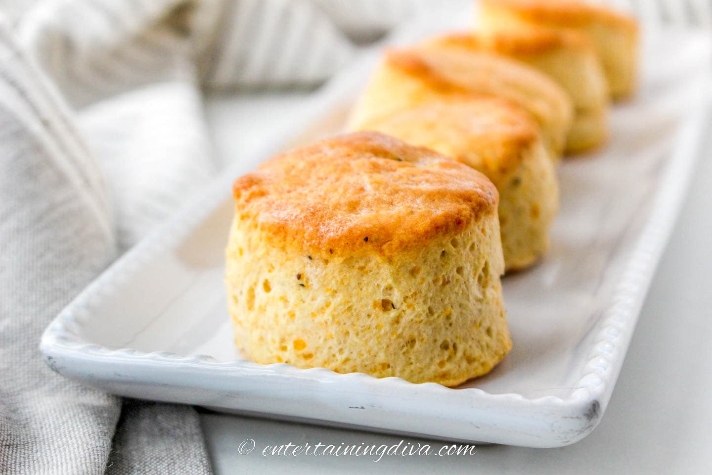 a row of homemade cheddar biscuits on a serving tray