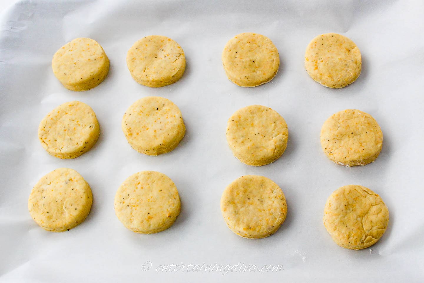 uncooked cheddar cheese biscuits on a baking sheet
