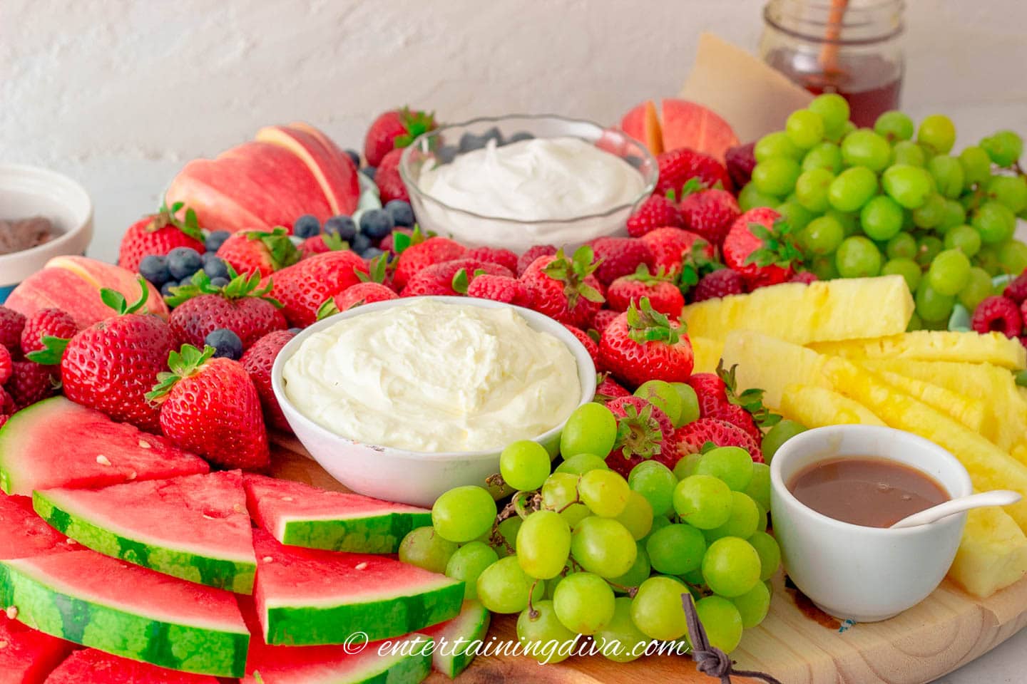 fruit charcuterie board with strawberries, grapes, blueberries, apples, pineapple and fruit dip