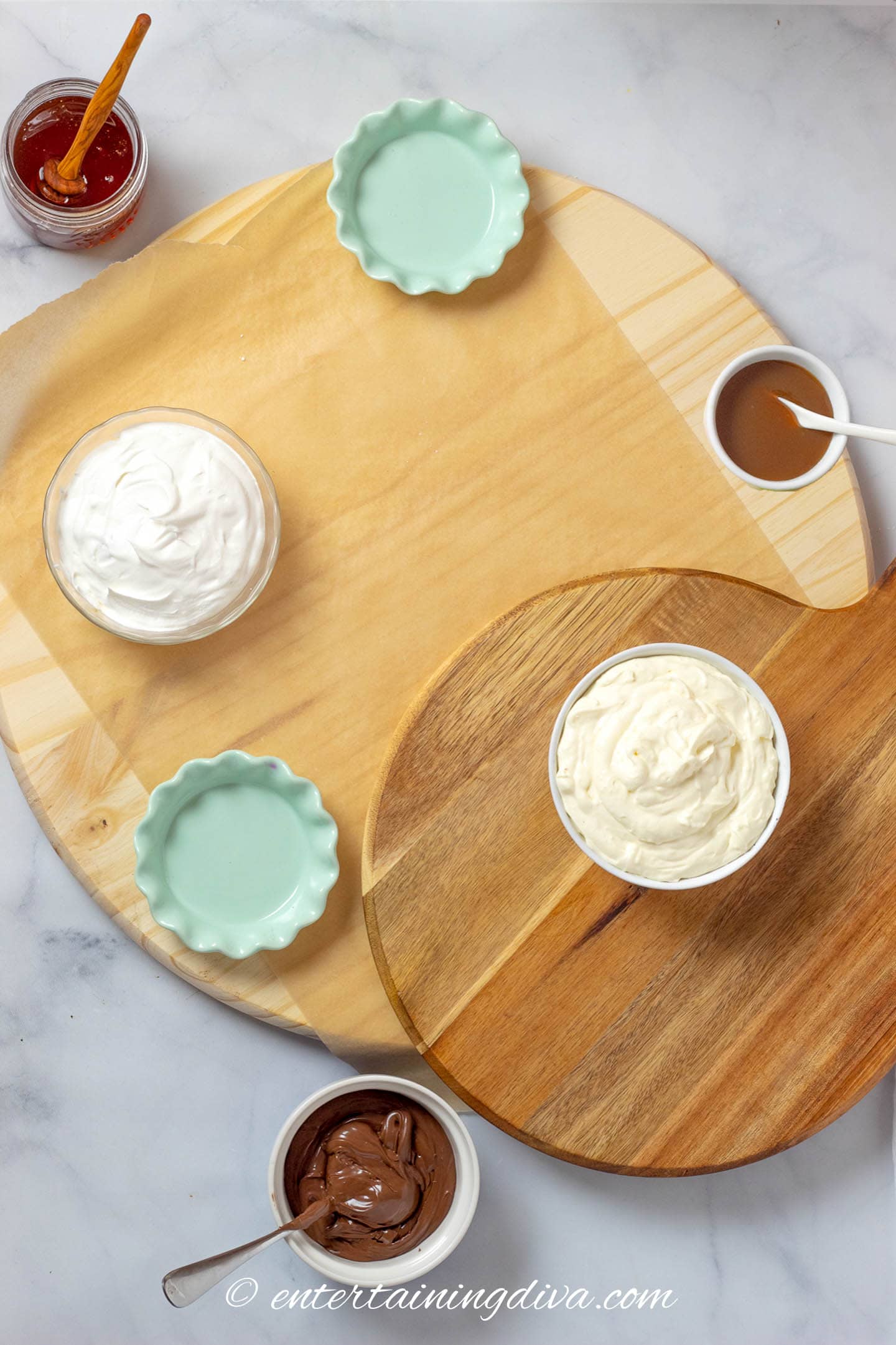 charcuterie board with bowls of dip - whipped cream, cream cheese fruit dip, hazelnut butter, honey and caramel