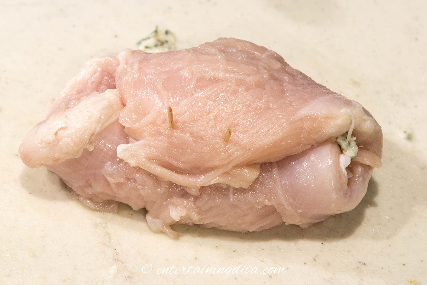 Raw chicken breast rolled up with toothpicks holding the ends closed