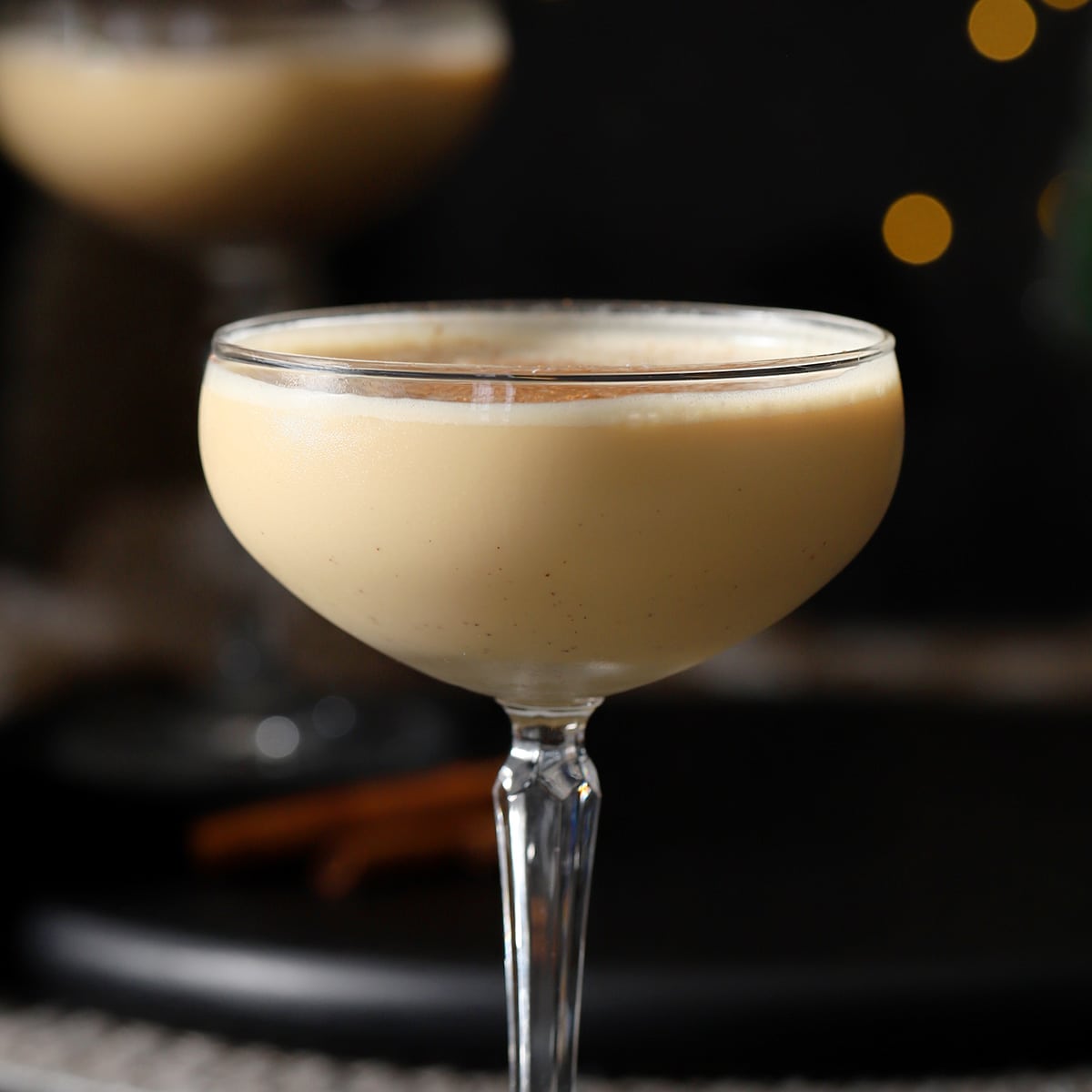 A cocktail in a glass with cinnamon sticks.