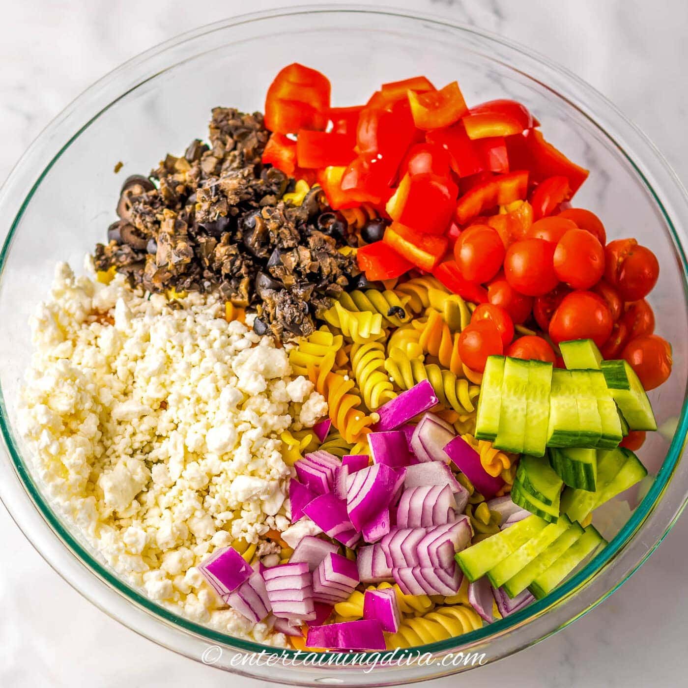 Greek pasta salad ingredients in a bowl