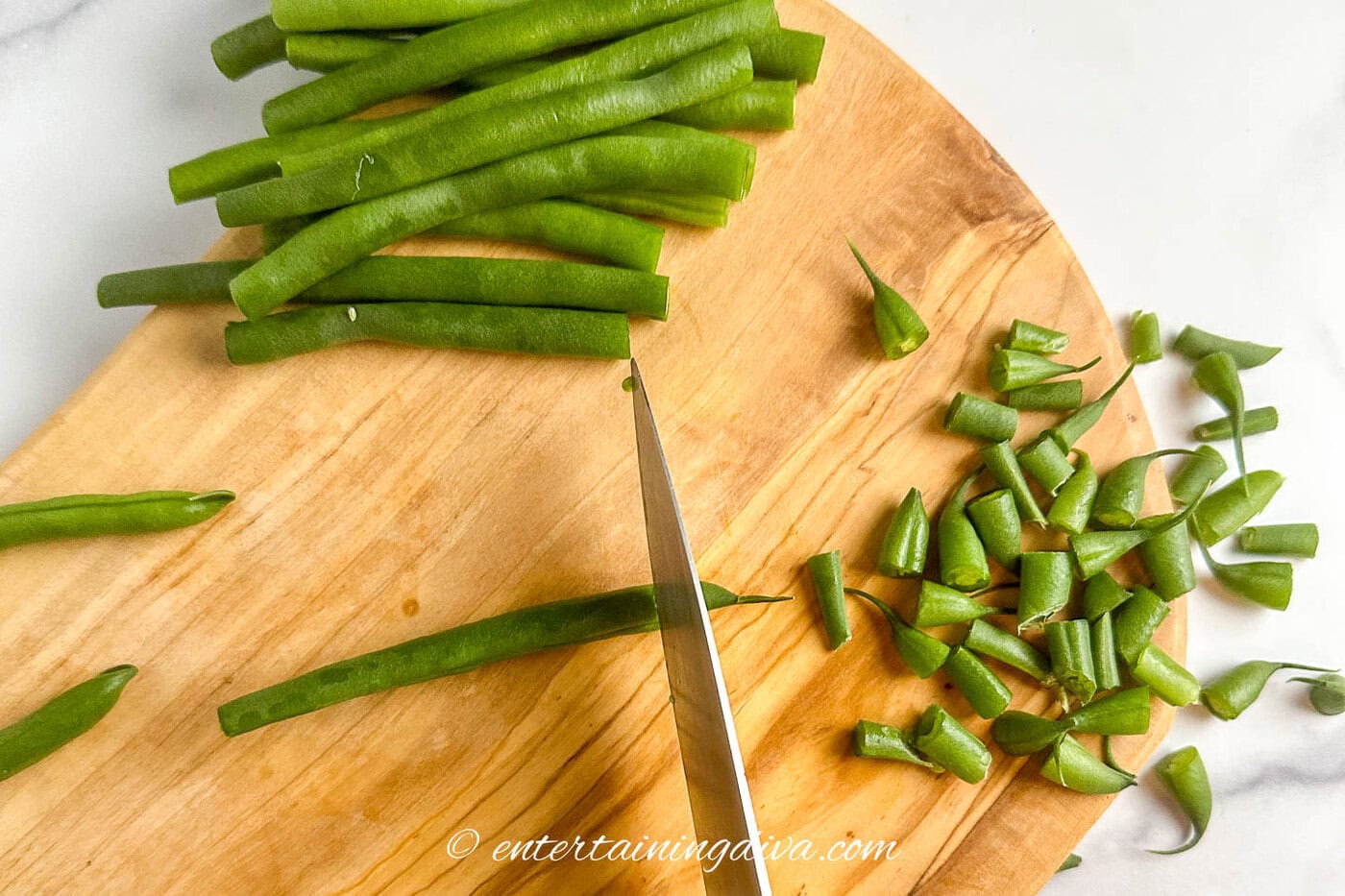 A knife cutting the ends off green beans
