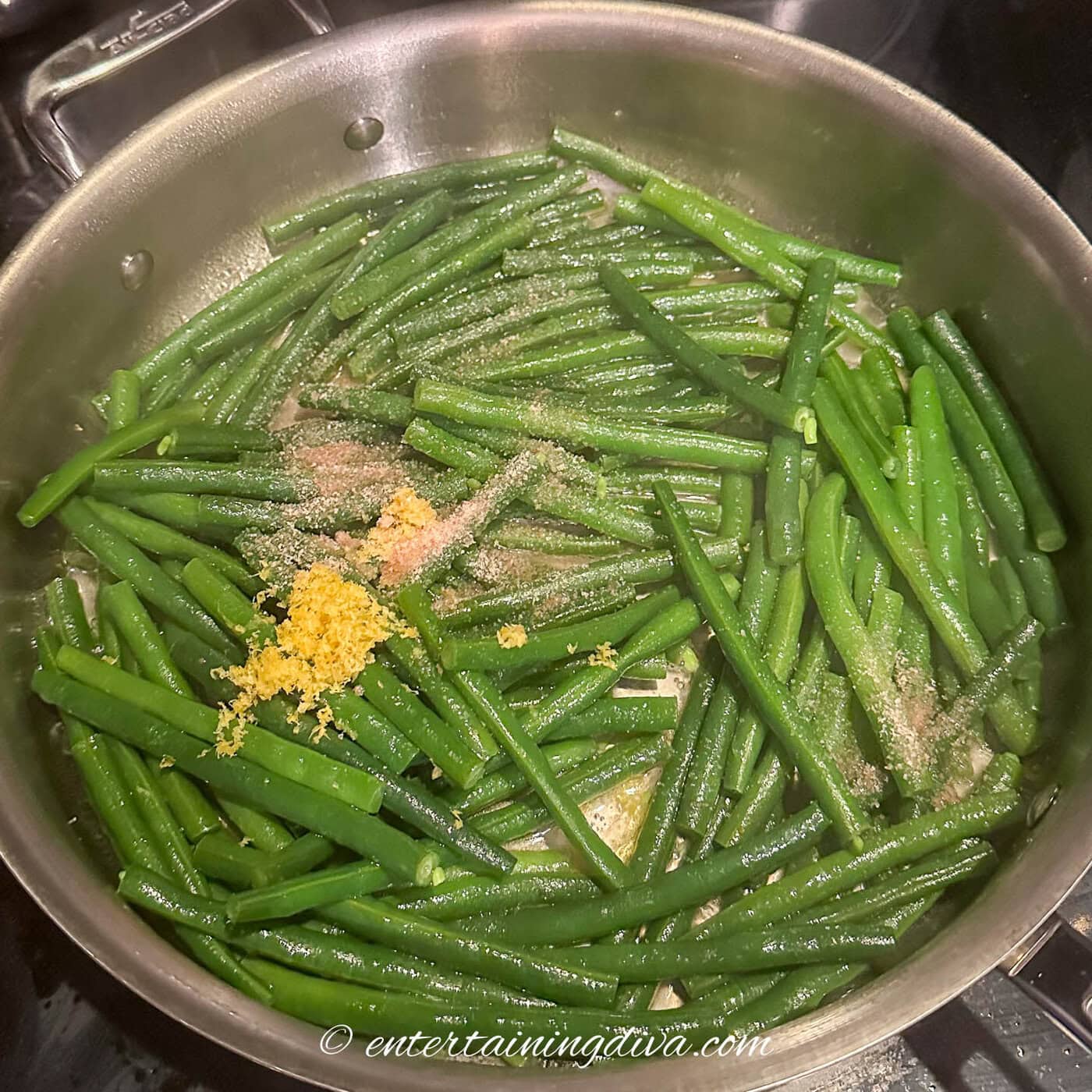 cooked green beans in a sauce pan with grated lemon zest and salt