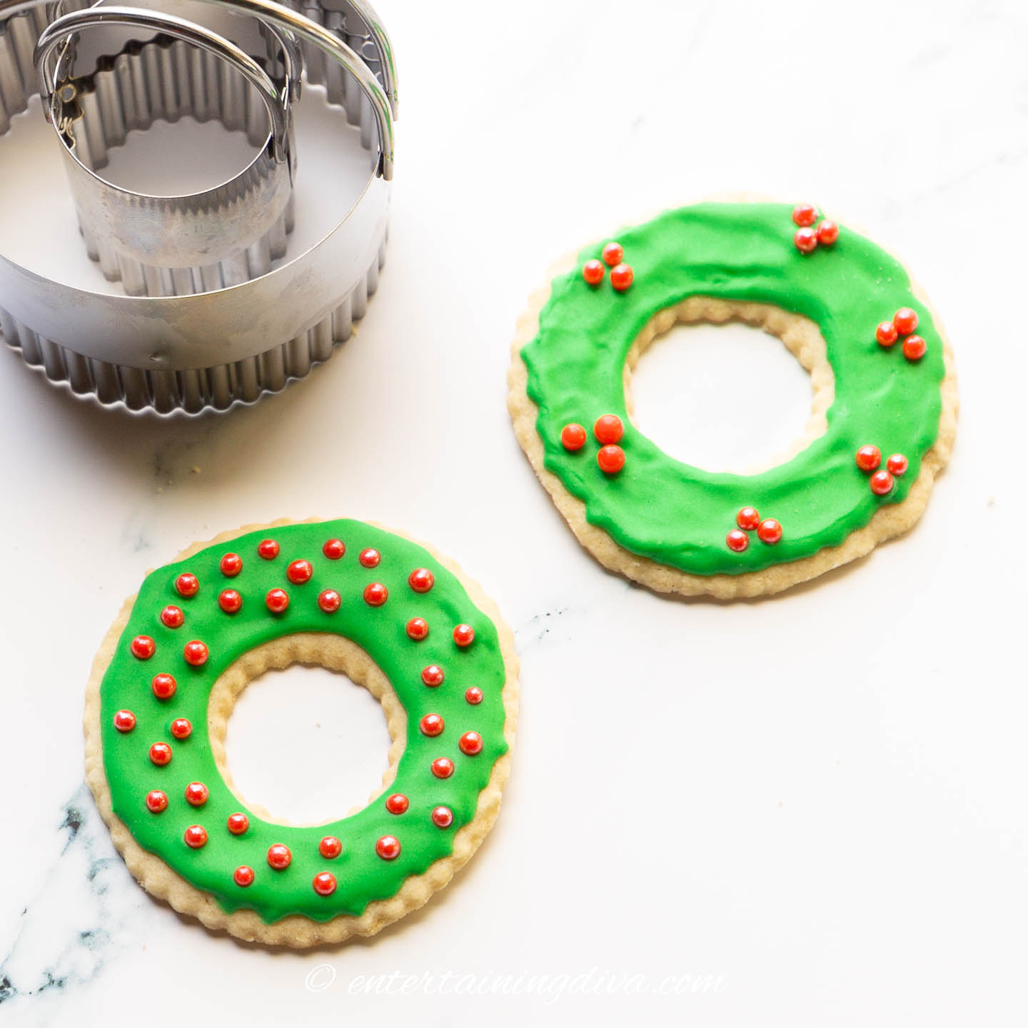 Christmas wreath sugar cookies decorated with green royal icing and red sugar balls