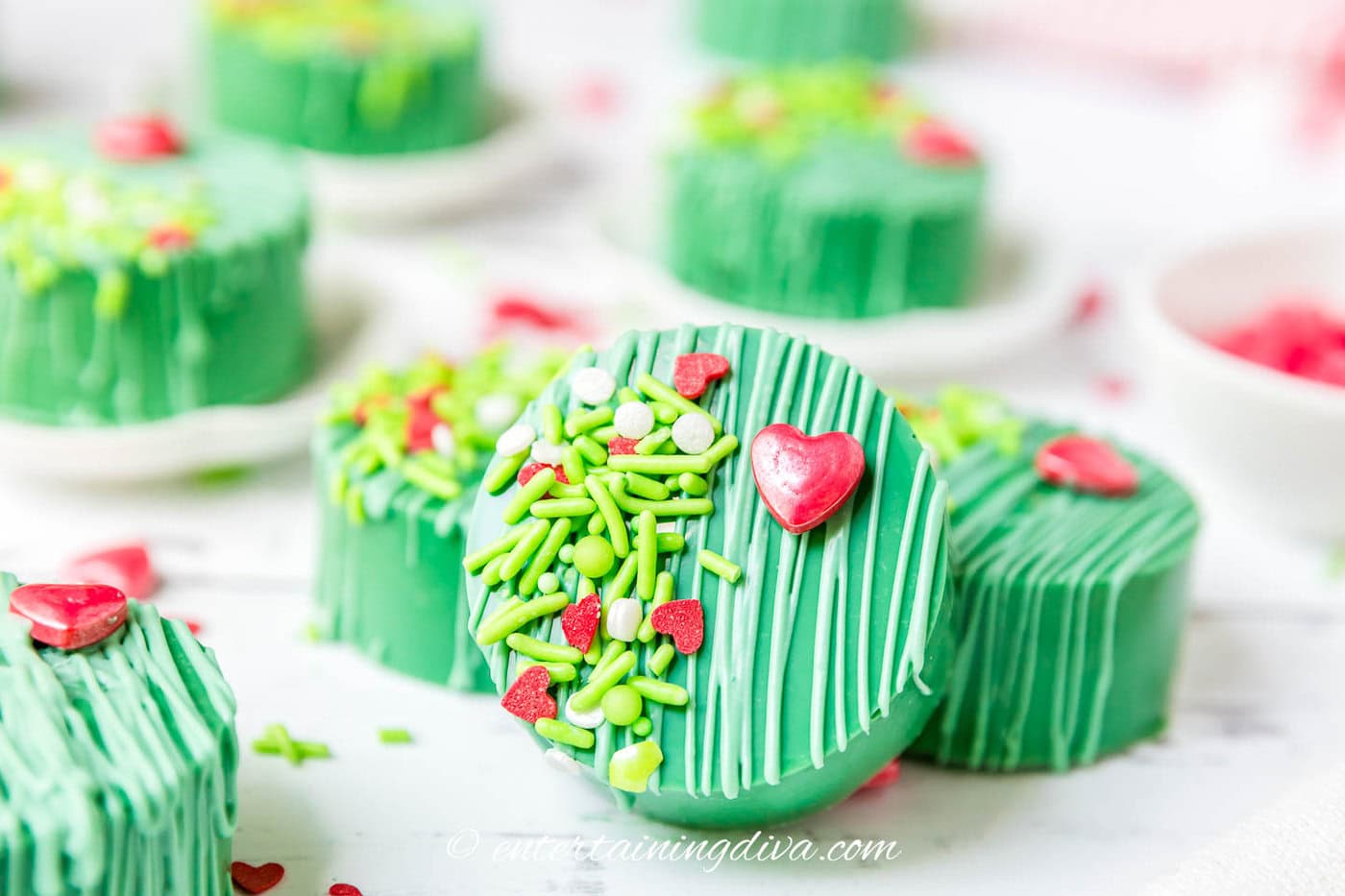 Close up of green Grinch cake pucks decorated with a red heart and sprinkles
