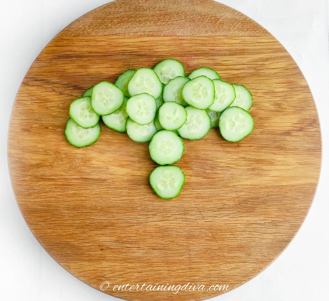 Cucumber slices arranged in a rounded T shape on a cutting board