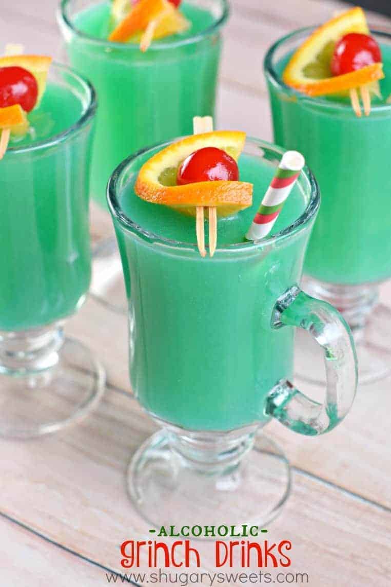 4 glasses of tropical Grinch cocktail garnished with an orange and maraschino cherry
