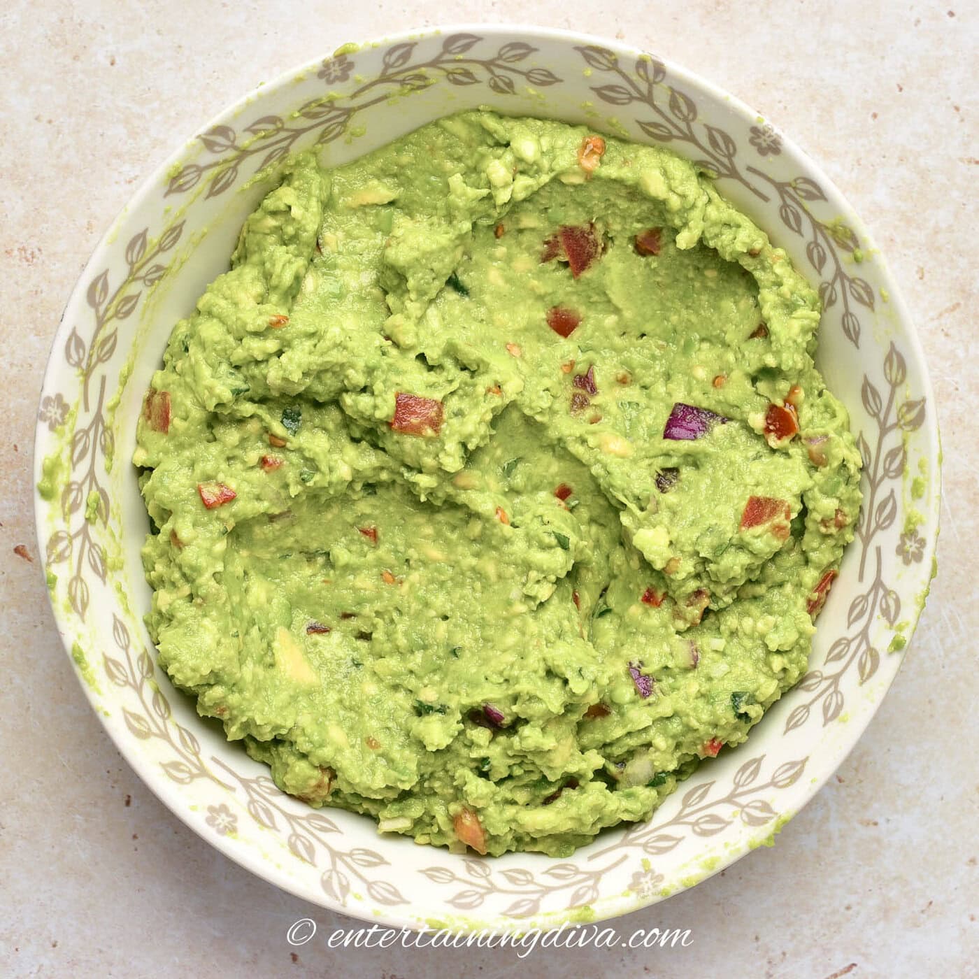 close up of avocado dip in a bowl with tortilla chipsin a bowl