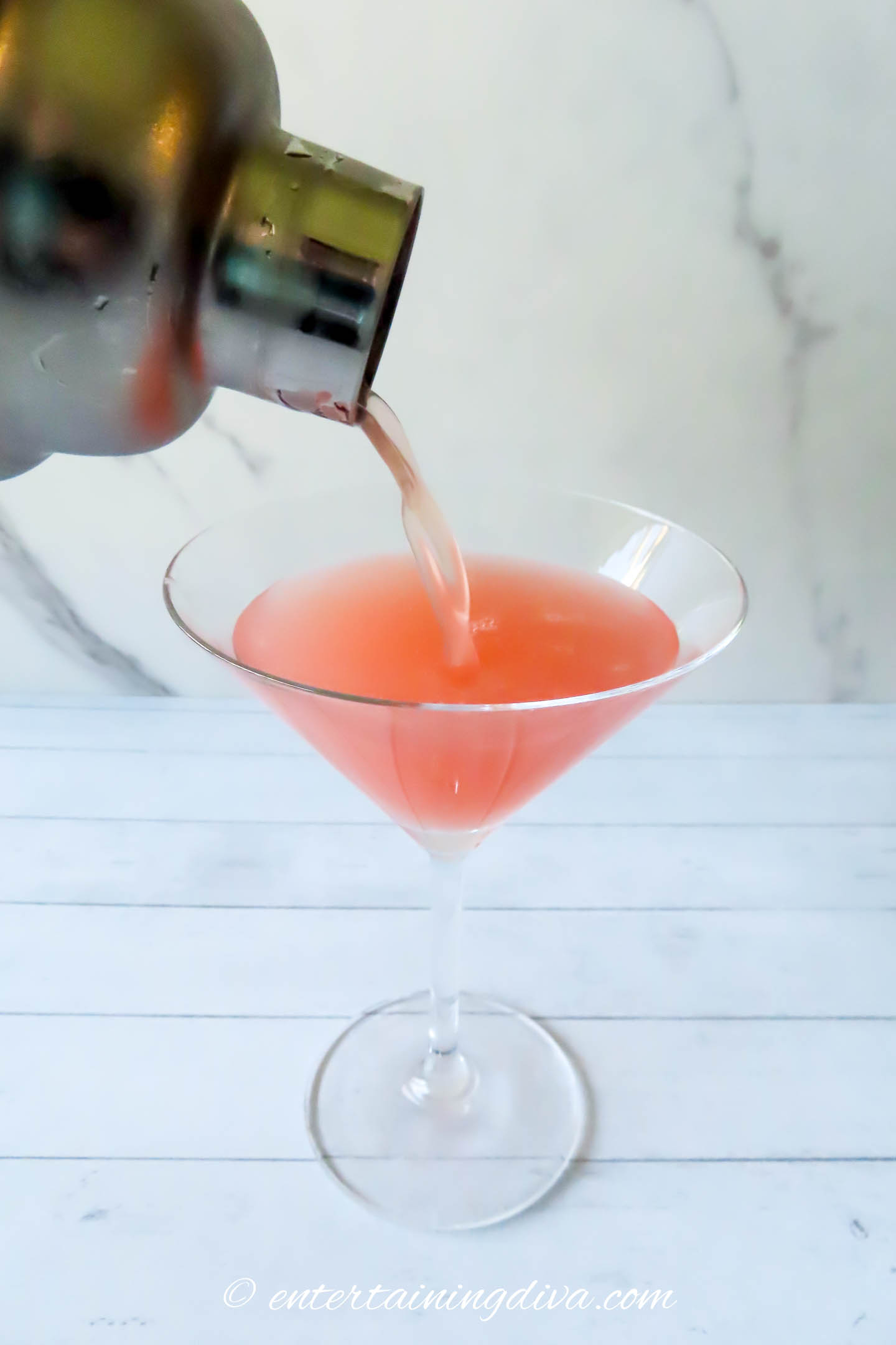 Mixed guava martini being poured into a glass